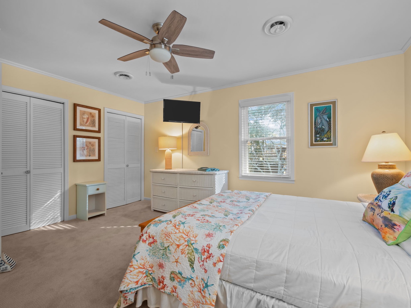 Drift off in your peaceful bedroom featuring a ceiling fan, flat-screen TV, and soft natural light from your window.