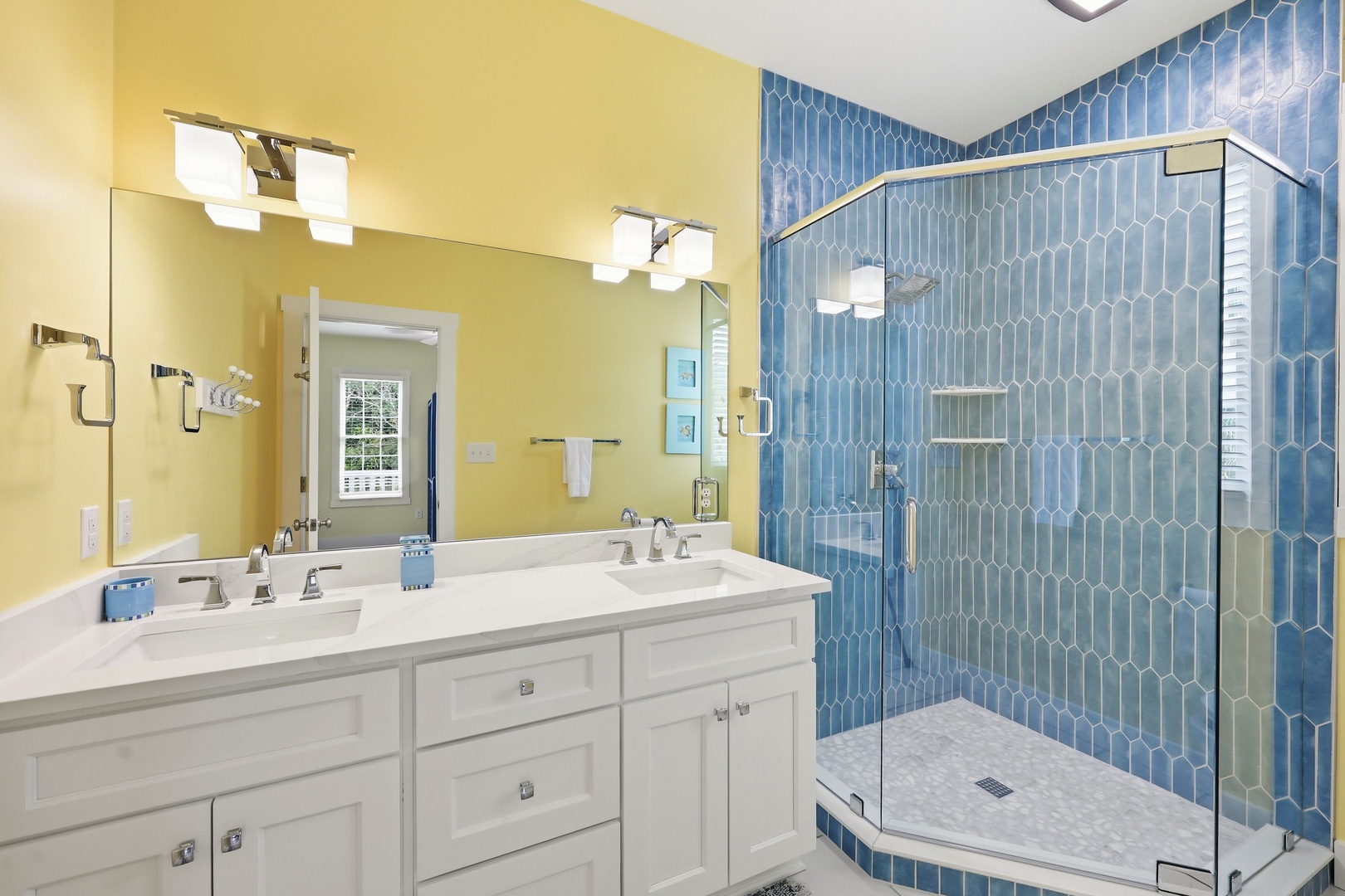 Step into your bright, modern bathroom with stunning blue hexagon tile shower, dual vanity sinks, and ample natural light streaming through the window.