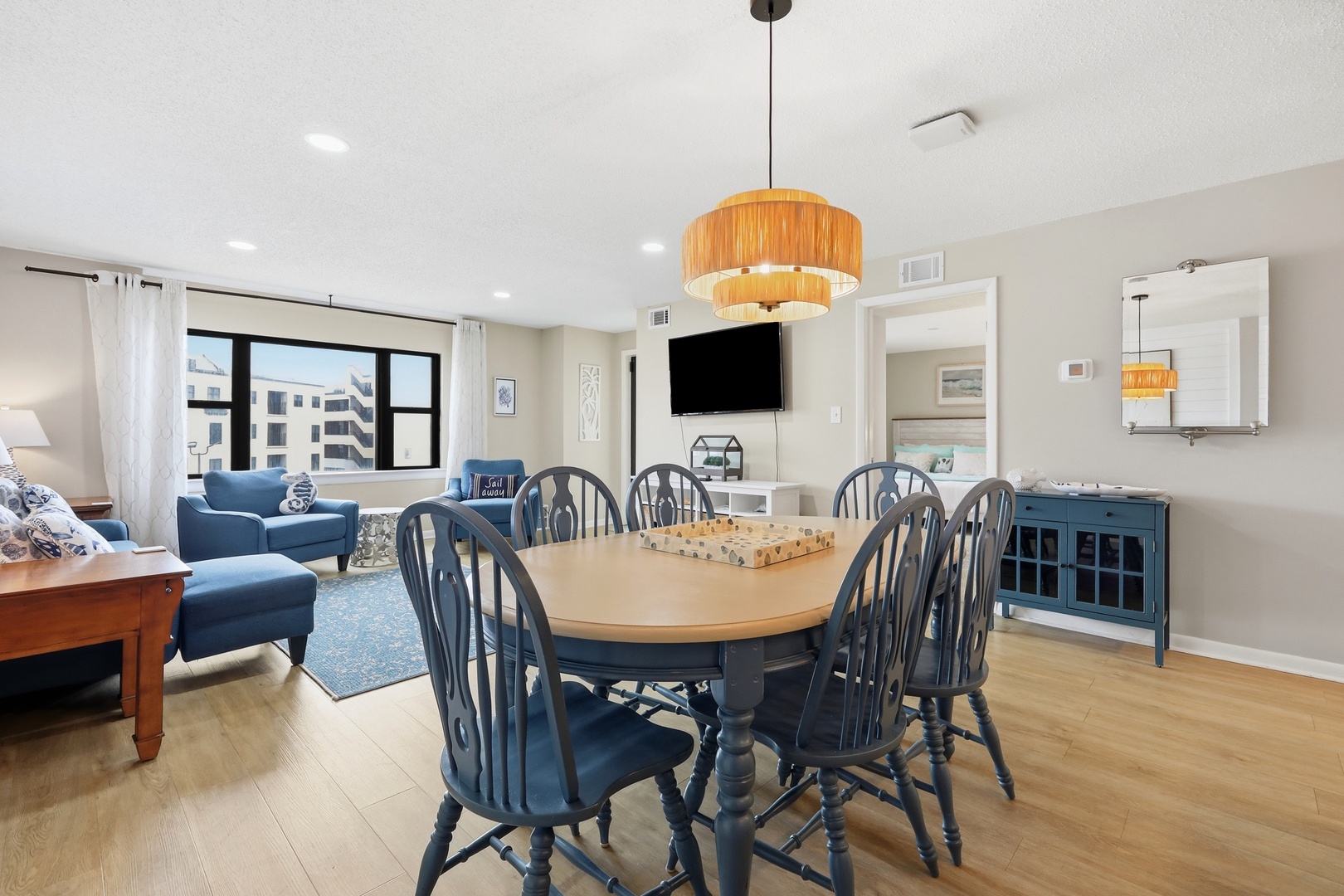 Gather around the spacious dining table with seating for eight, where natural light streams in and inviting blue armchairs beckon you to unwind in the open-concept living area.