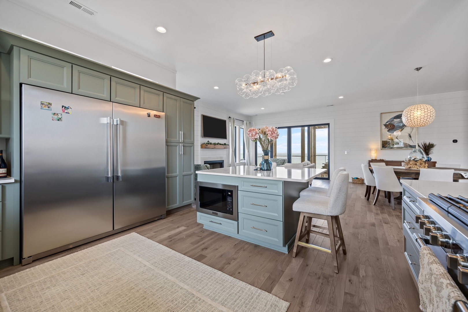 Your gourmet kitchen invites culinary adventures with gleaming appliances, elegant island seating, and sparkling chandeliers creating the perfect gathering space.