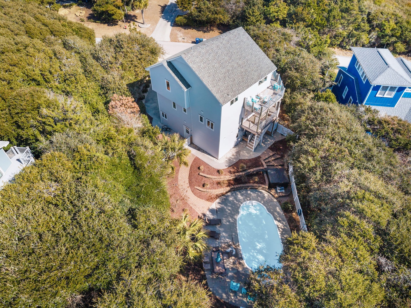 Aerial view of vacation rental property featuring private pool surrounded by lush coastal vegetation and natural landscape.