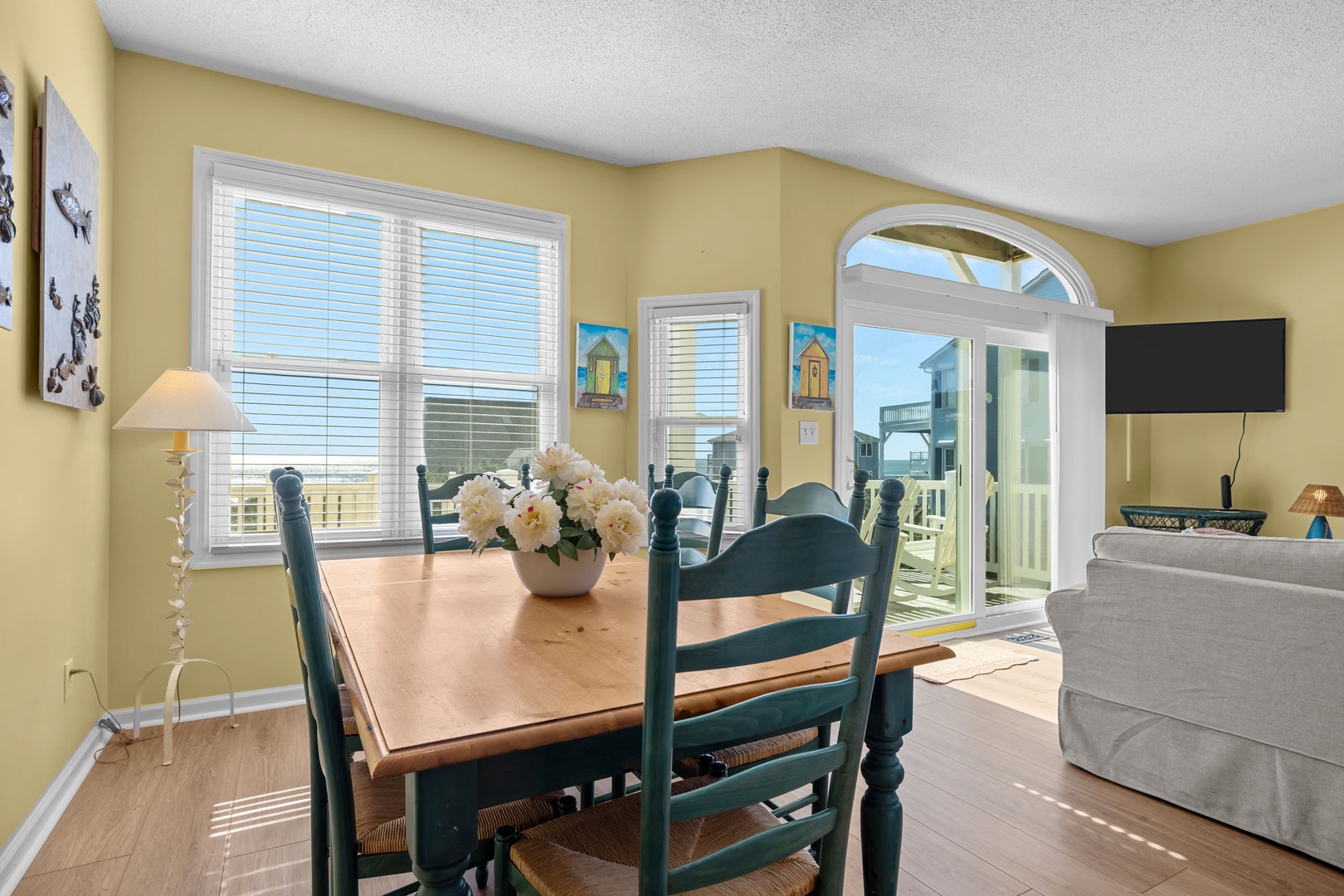 Enjoy meals at your charming wooden dining table with coastal charm, where fresh flowers and warm yellow walls create a welcoming atmosphere.