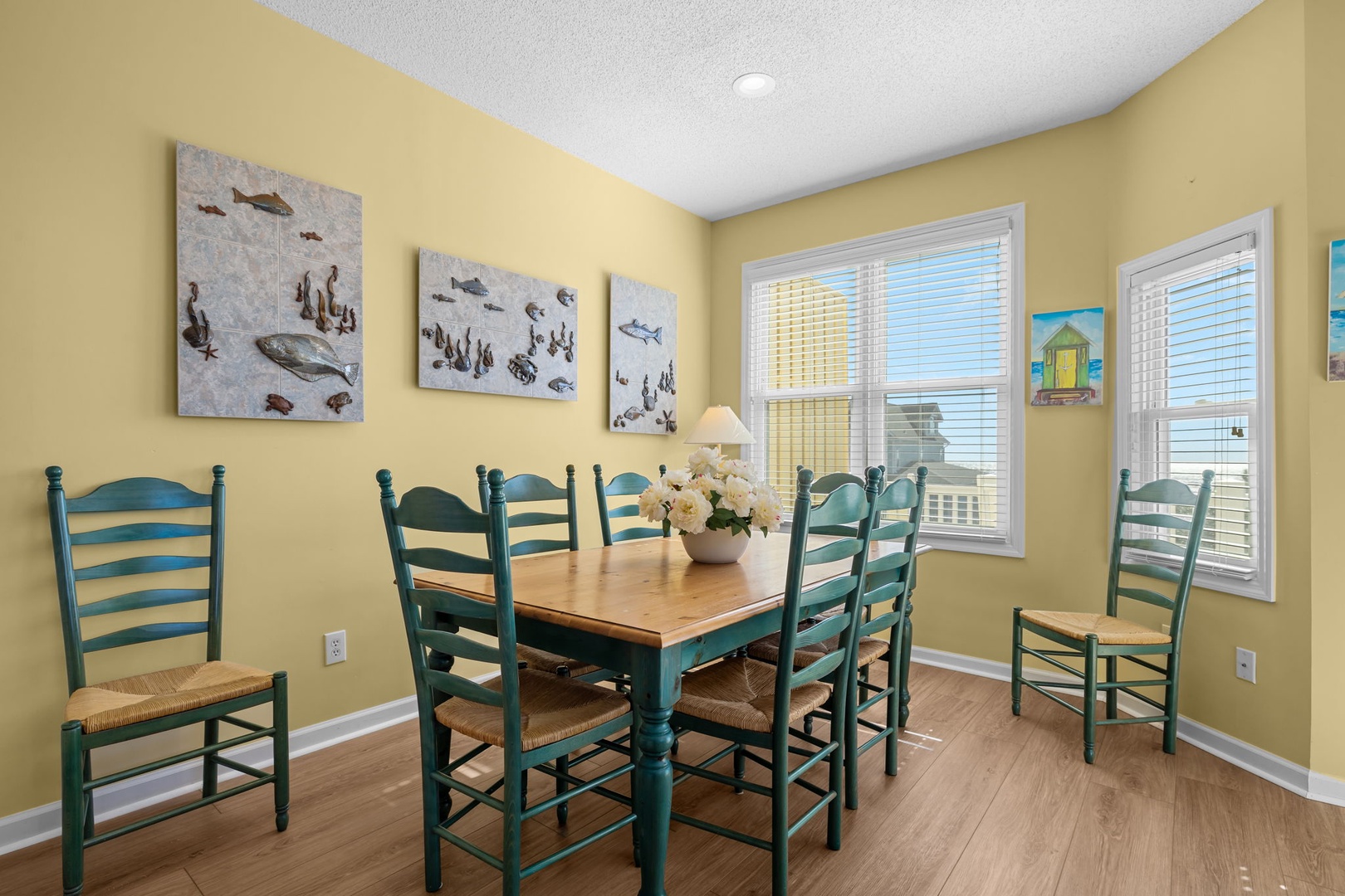 Gather around this charming dining table where coastal artwork and warm yellow walls create the perfect backdrop for your memorable meals together.