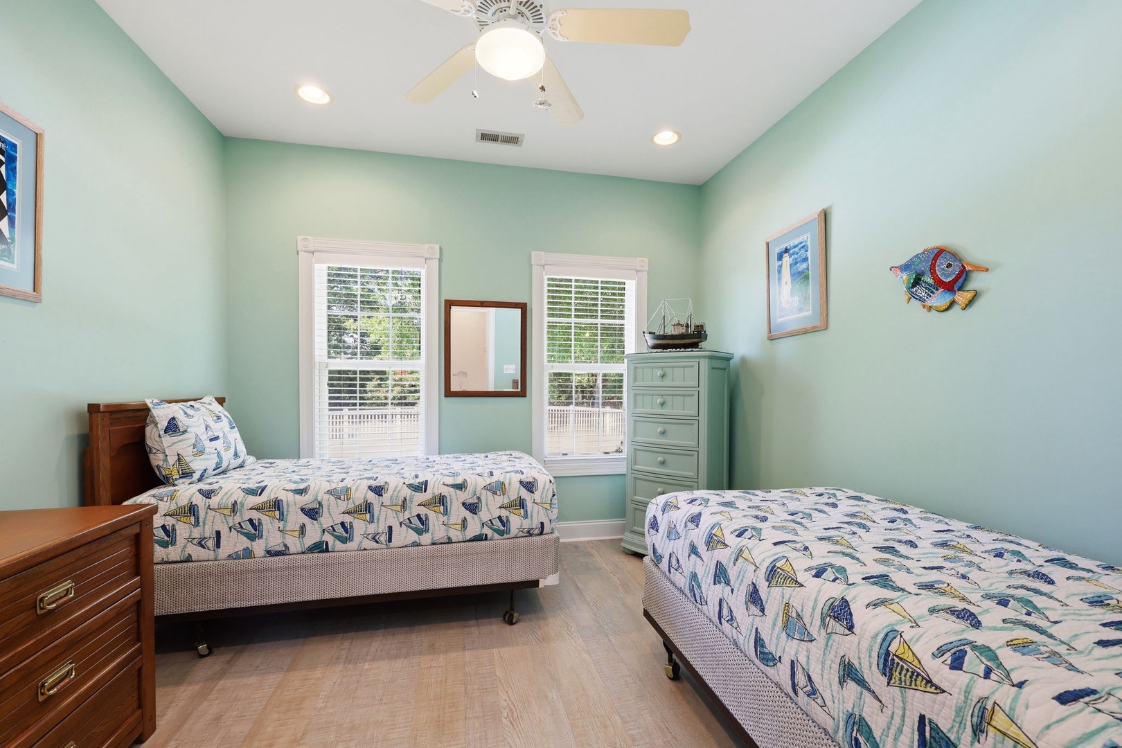 Relax in your breezy coastal bedroom with twin beds, ceiling fan, and cheerful nautical touches. Natural light fills the space with a welcoming, airy feel.