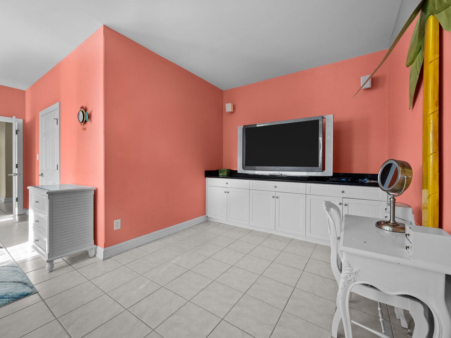 Relax in your vibrant living space where coral walls create warmth and white furnishings offer comfort for movie nights and peaceful moments.