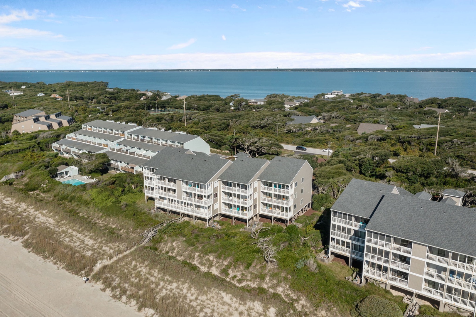 Beachfront resort buildings nestled among coastal vegetation with direct ocean access and scenic dune landscapes.