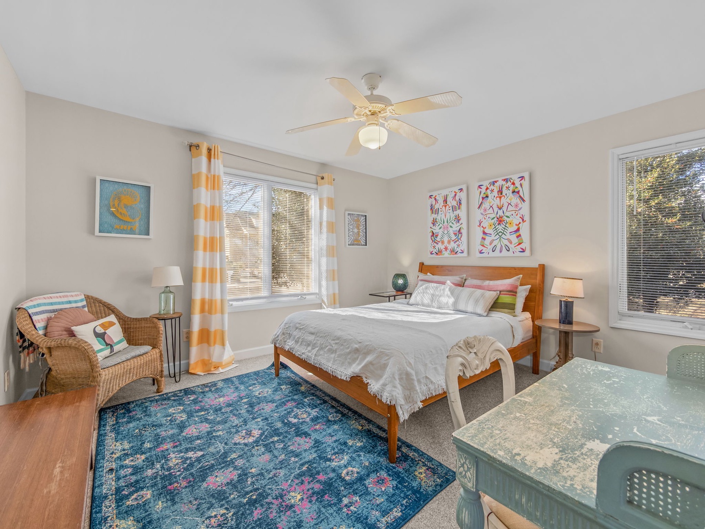 Sink into comfort in your bright bedroom featuring cheerful artwork, cozy seating, and windows that fill the space with natural light.
