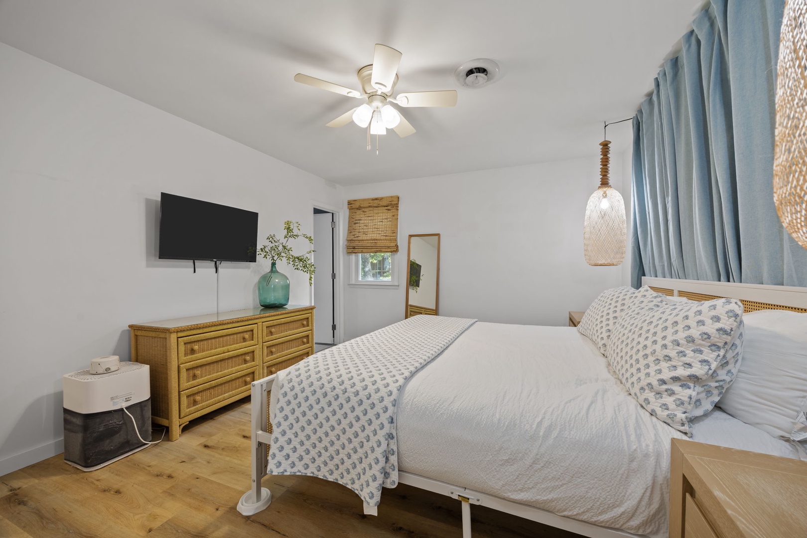 Drift off in your serene coastal bedroom with crisp linens, warm wood accents, and gentle ceiling fan keeping you comfortable.