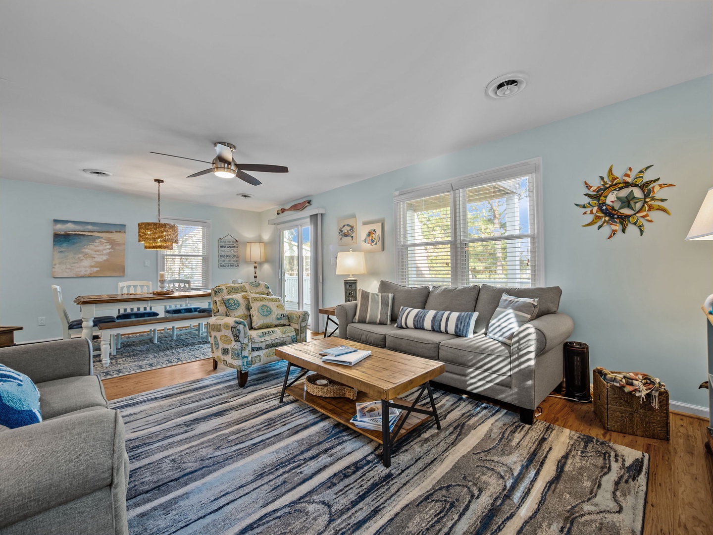 Your bright, coastal-inspired living space welcomes you with soft blues, comfortable seating, and natural light streaming through large windows.