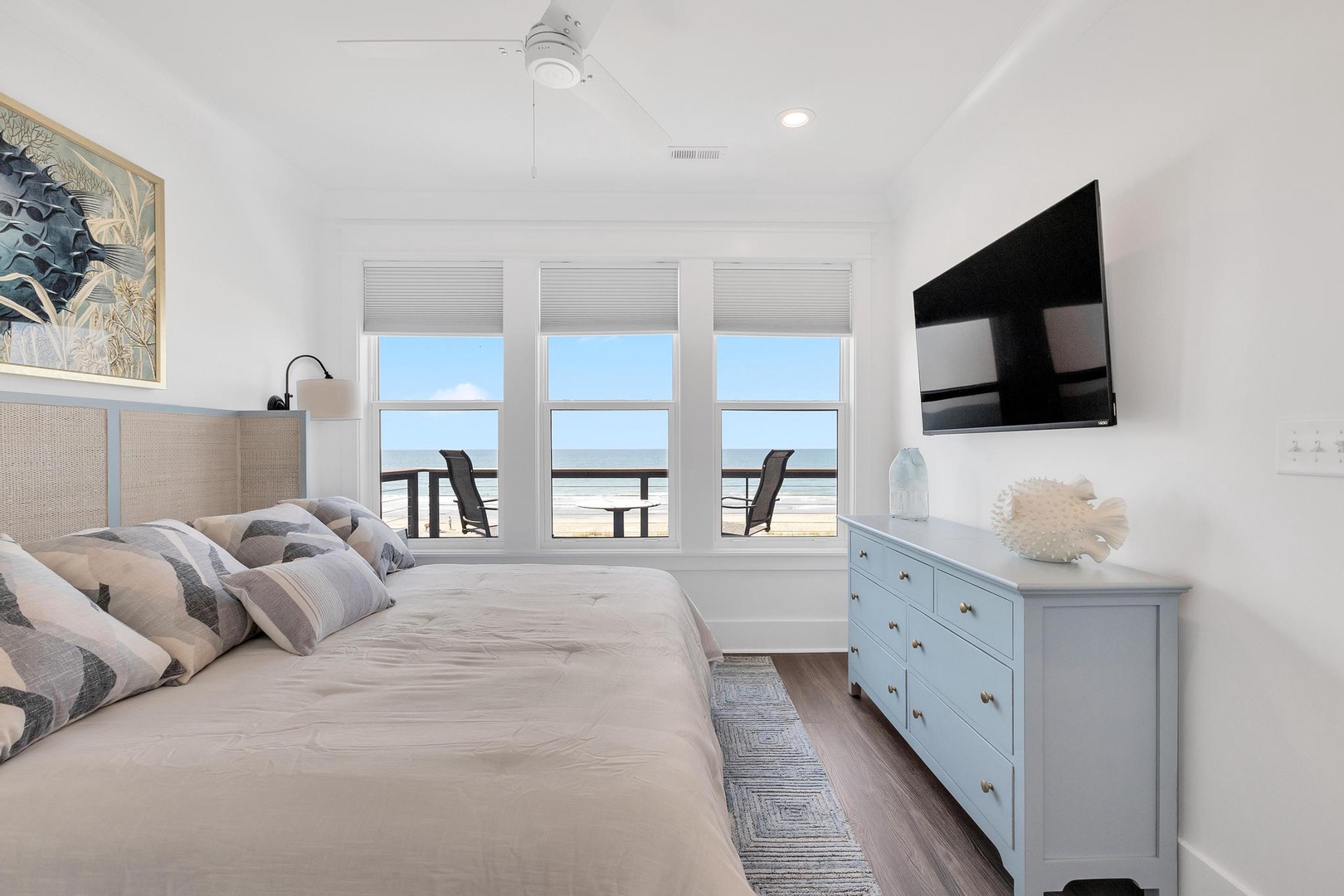 Picture yourself waking to sweeping ocean views through triple windows, your coastal retreat bathed in natural light. Plush bedding and calming blues create your perfect beach escape.
