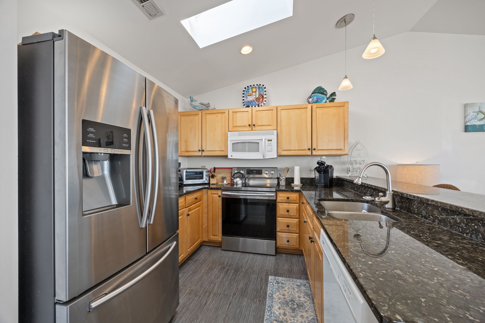Your fully equipped kitchen features stainless steel appliances and granite counters, perfect for preparing meals with natural light streaming through the skylight.