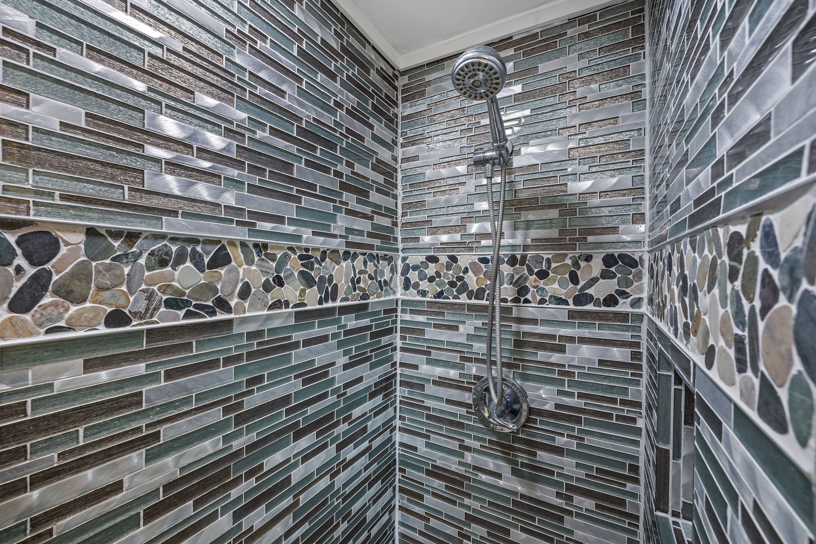 Step into your beautifully tiled shower featuring stunning glass mosaic walls and natural stone accents that create a spa-like retreat.