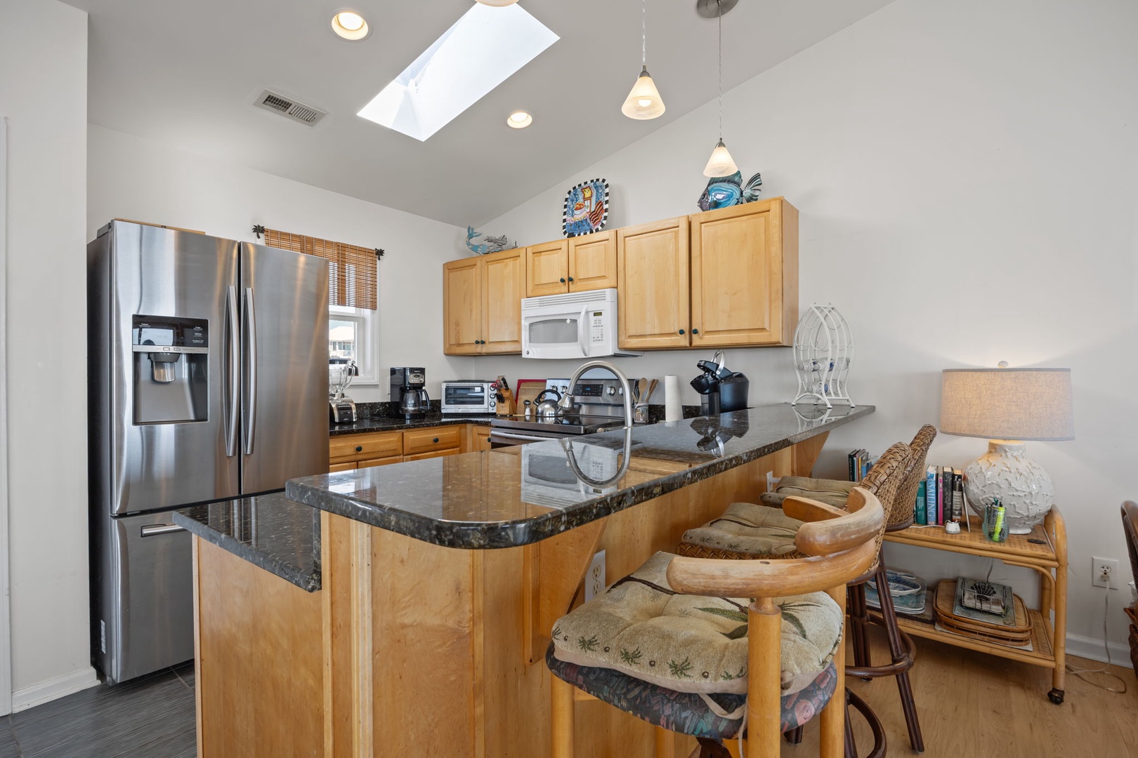 Your bright, fully-equipped kitchen invites culinary adventures with granite countertops, stainless steel appliances, and a sunny skylight overhead.