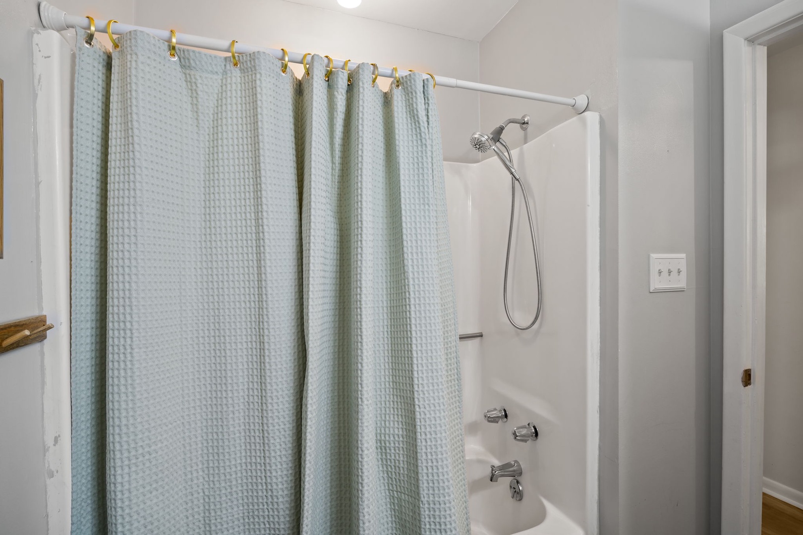 Step into your private bathroom featuring a spacious tub-shower combo with refreshing rainfall showerhead and soft spa-like curtain for ultimate relaxation.