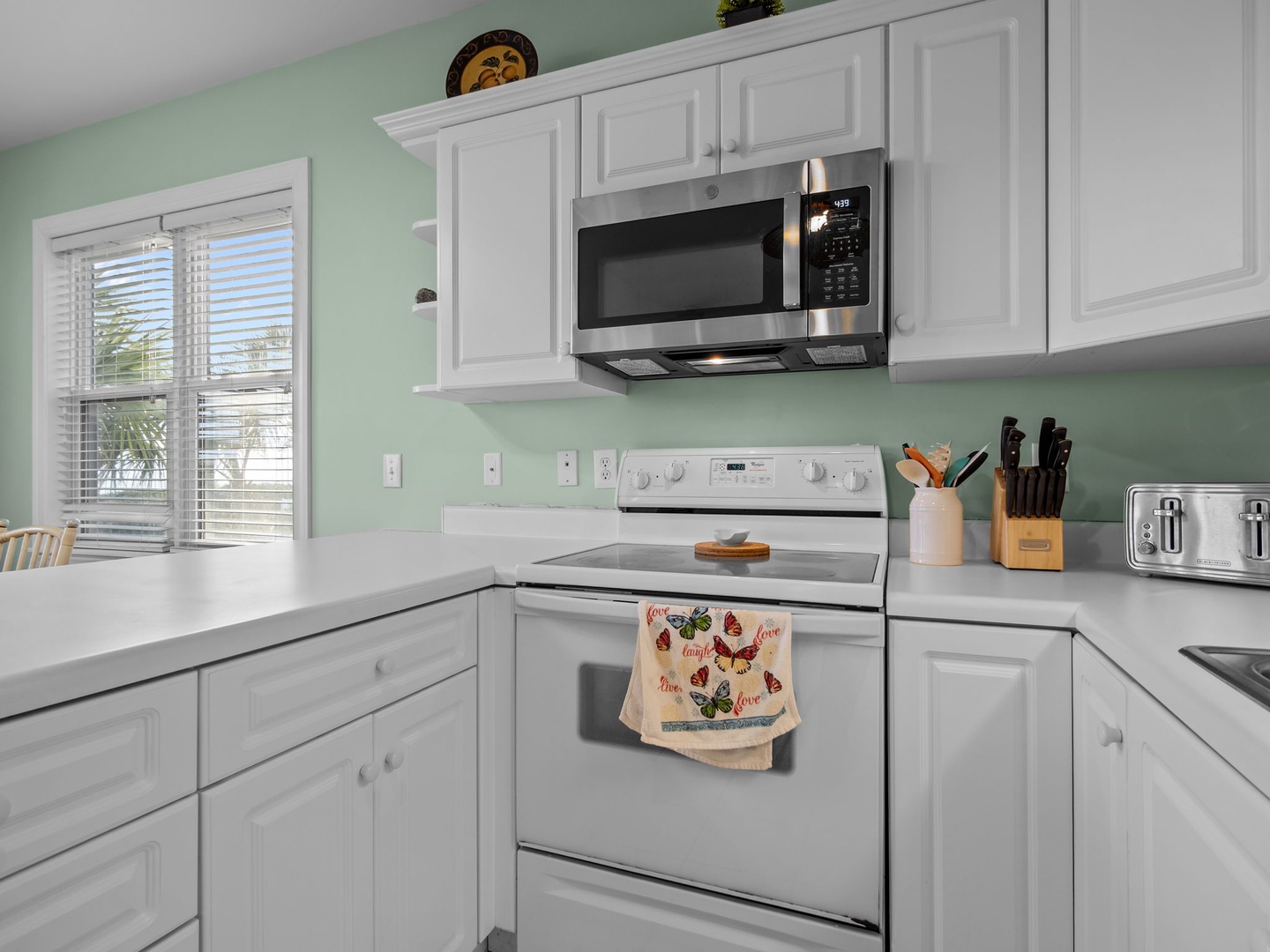 Your fully equipped kitchen features crisp white cabinets, stainless appliances, and soothing mint walls—perfect for preparing morning coffee or home-cooked meals.