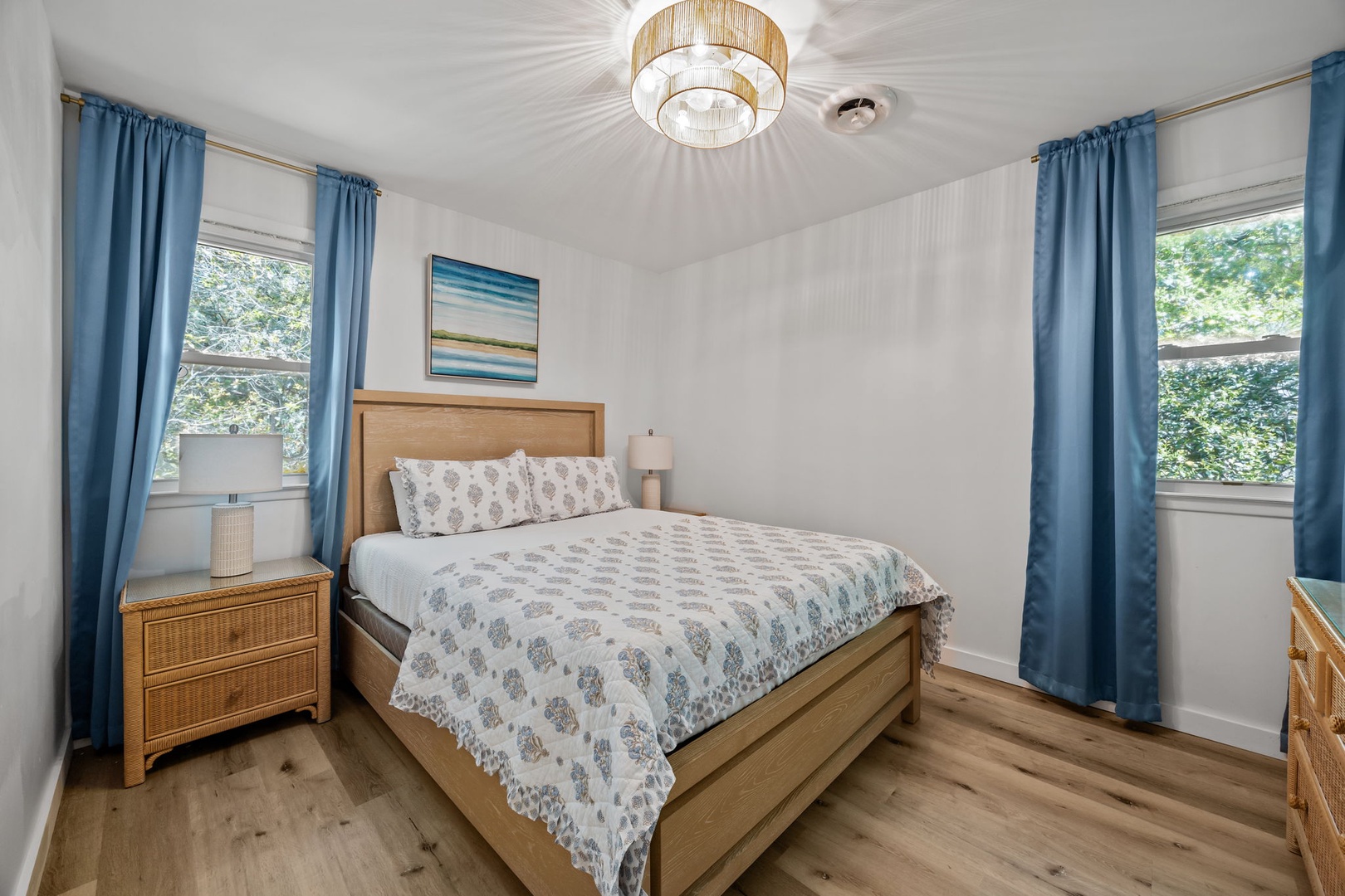 Your peaceful bedroom features warm wood furnishings and soft blue accents, with natural light streaming through dual windows for restful mornings.