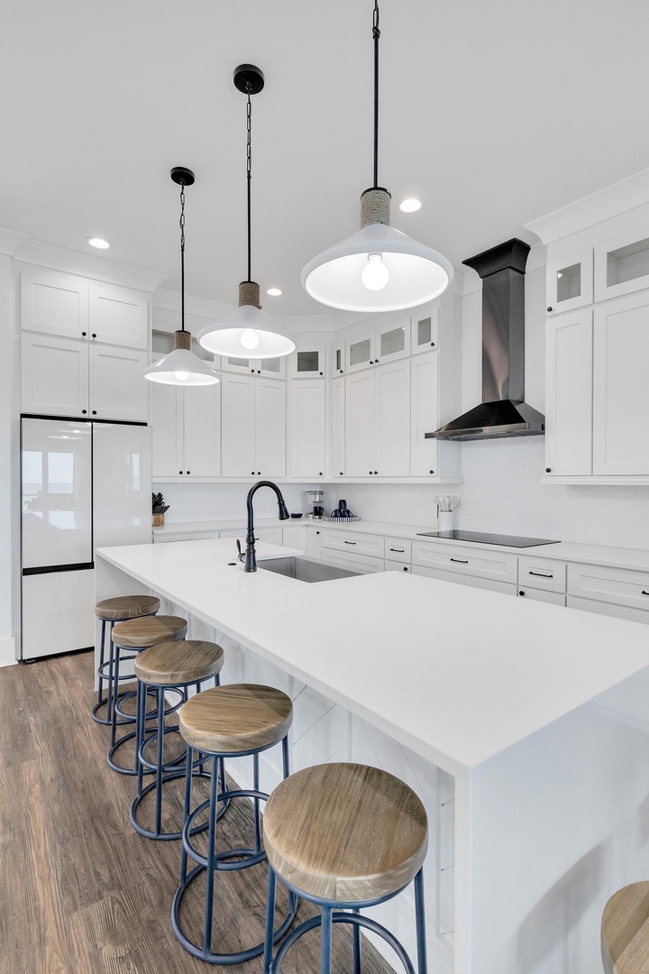 Gather around this sleek kitchen island where crisp white cabinetry meets warm wood accents. Stylish pendant lights illuminate your culinary creations in this beautifully designed space.