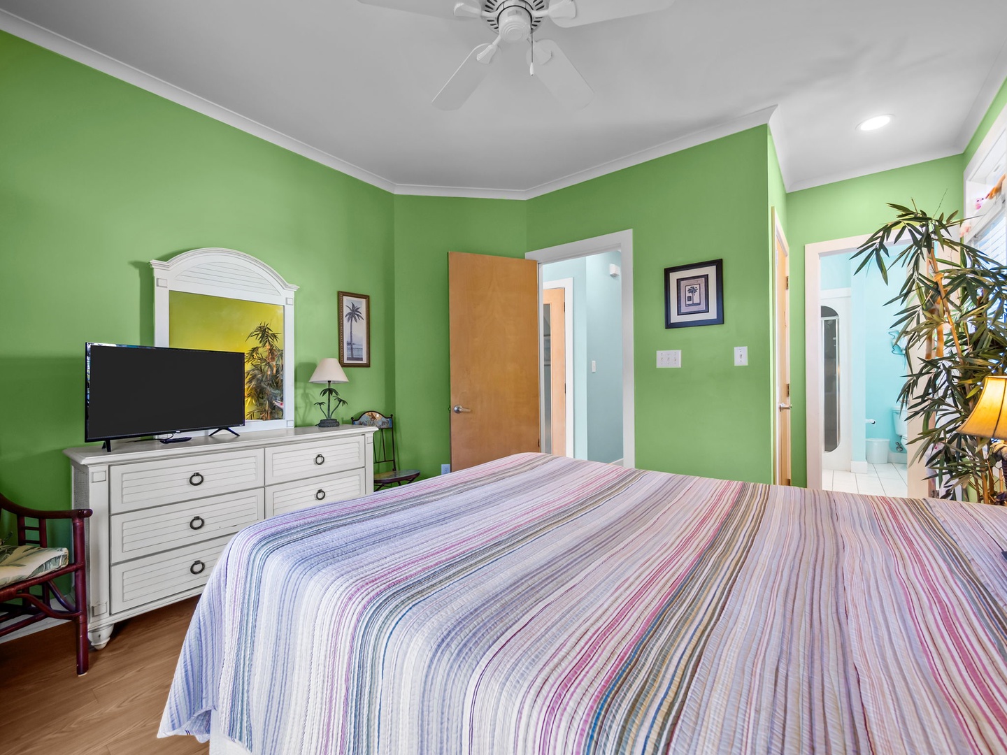 Unwind in your vibrant retreat with cheerful green walls, comfortable bedding, and tropical touches that create a refreshing escape.