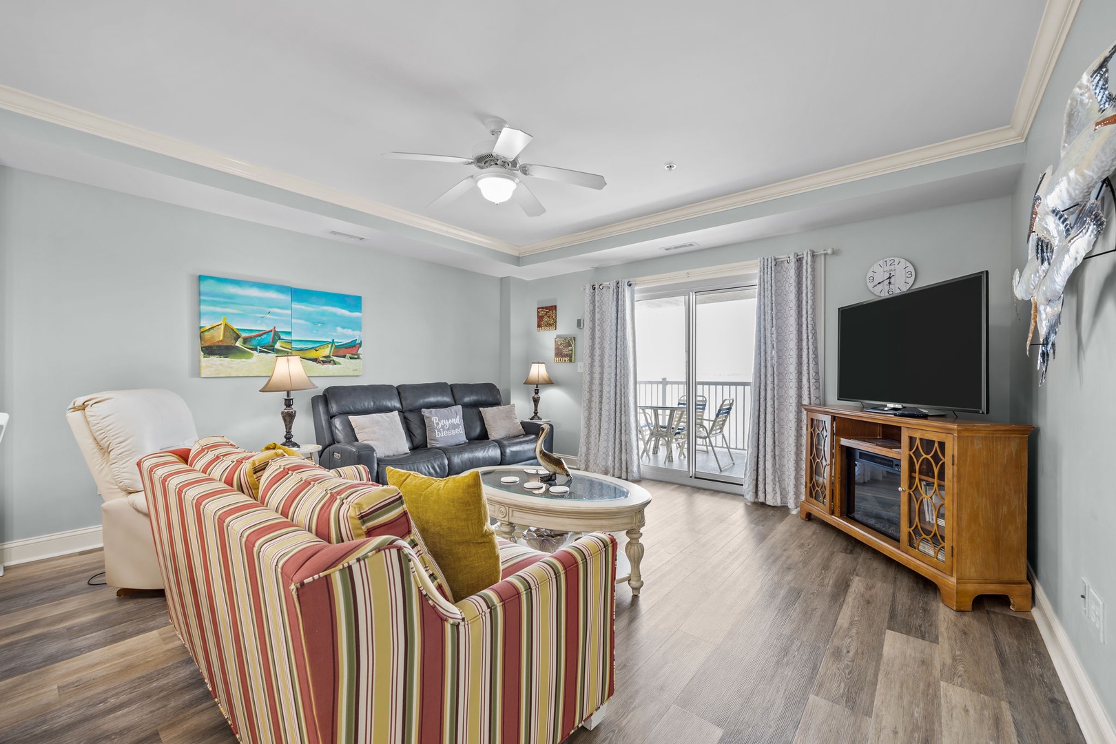 Relax in your bright living room featuring coastal artwork, comfy seating, and a balcony with scenic views.