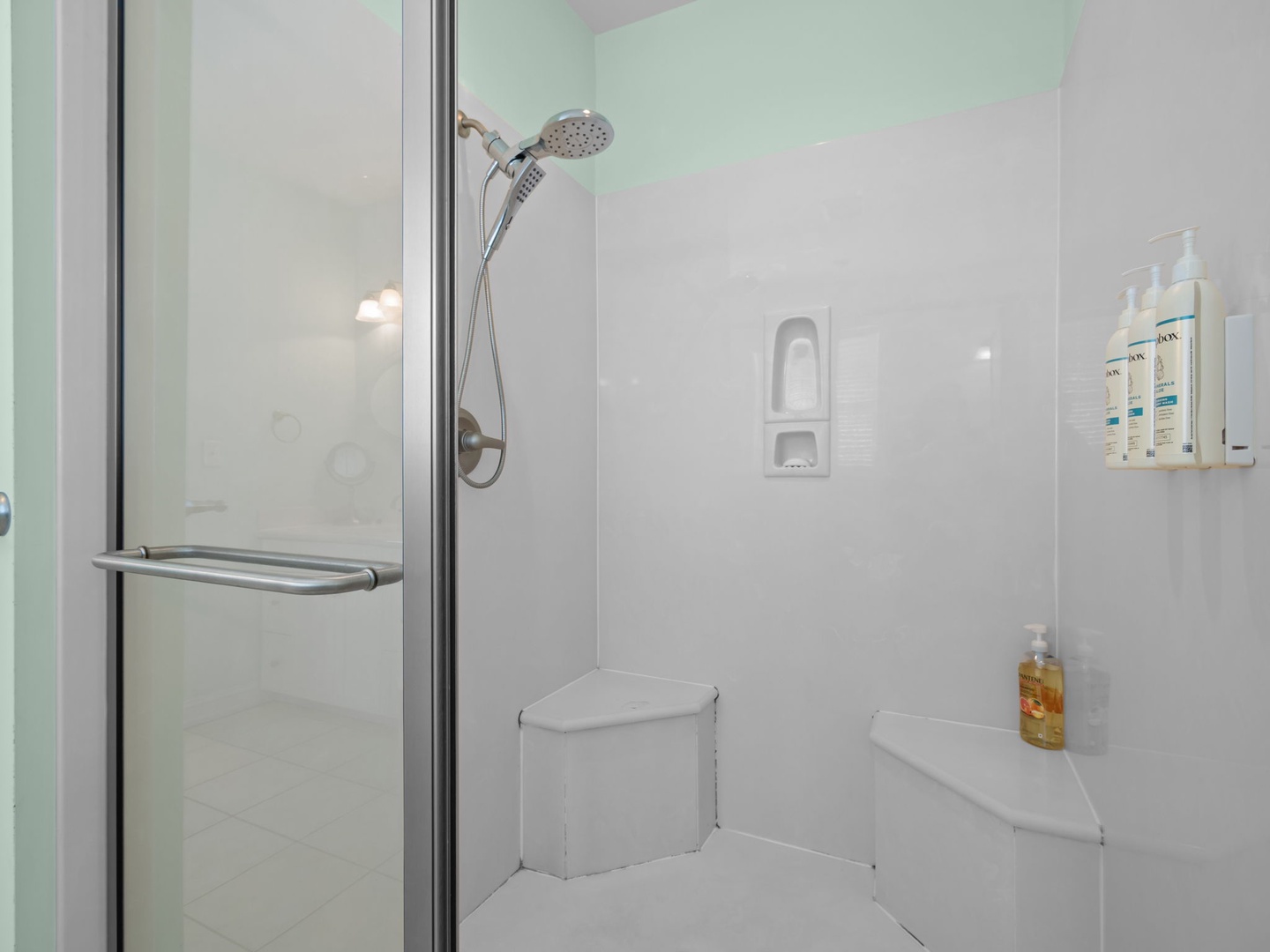 Step into your pristine shower with modern fixtures and convenient corner seating for ultimate relaxation.