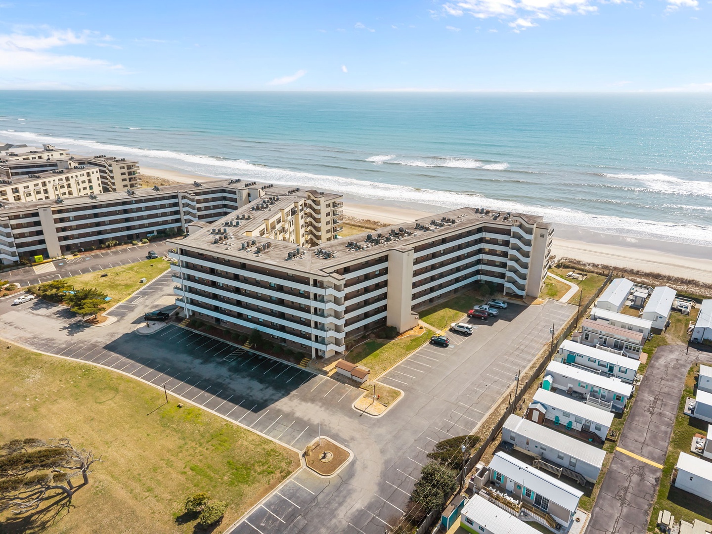 Beachfront property positioned directly along pristine sandy shores, featuring modern multi-story buildings with convenient parking and easy beach access in a tranquil coastal setting.