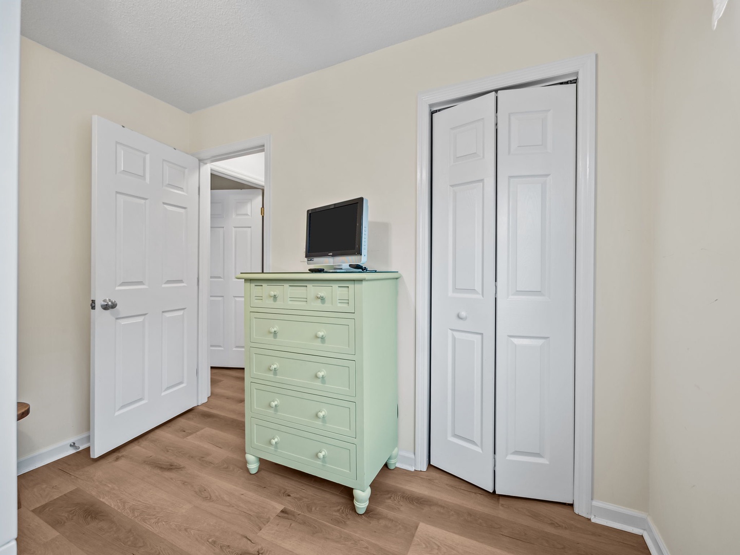 Unpack your belongings in this charming bedroom corner with ample storage in the mint-green dresser and convenient TV for evening relaxation.