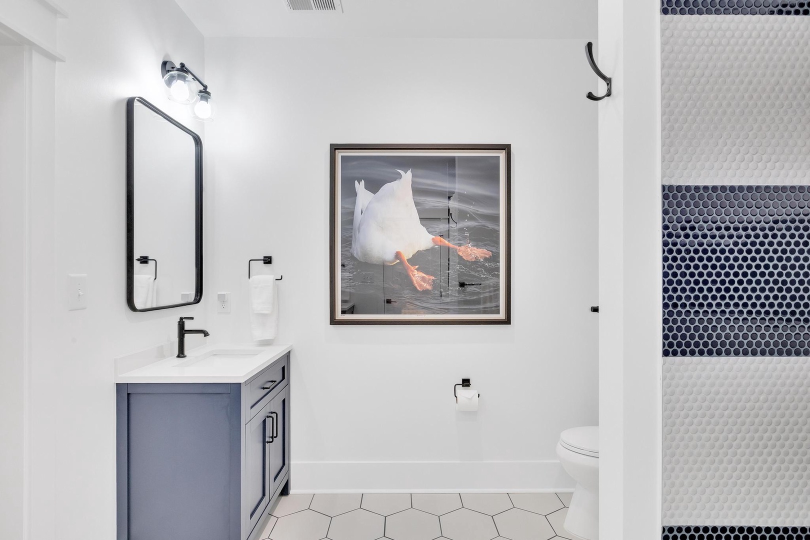 Step into your modern sanctuary with bold mosaic tile, sleek black fixtures, and artistic touches that bring personality to every detail.
