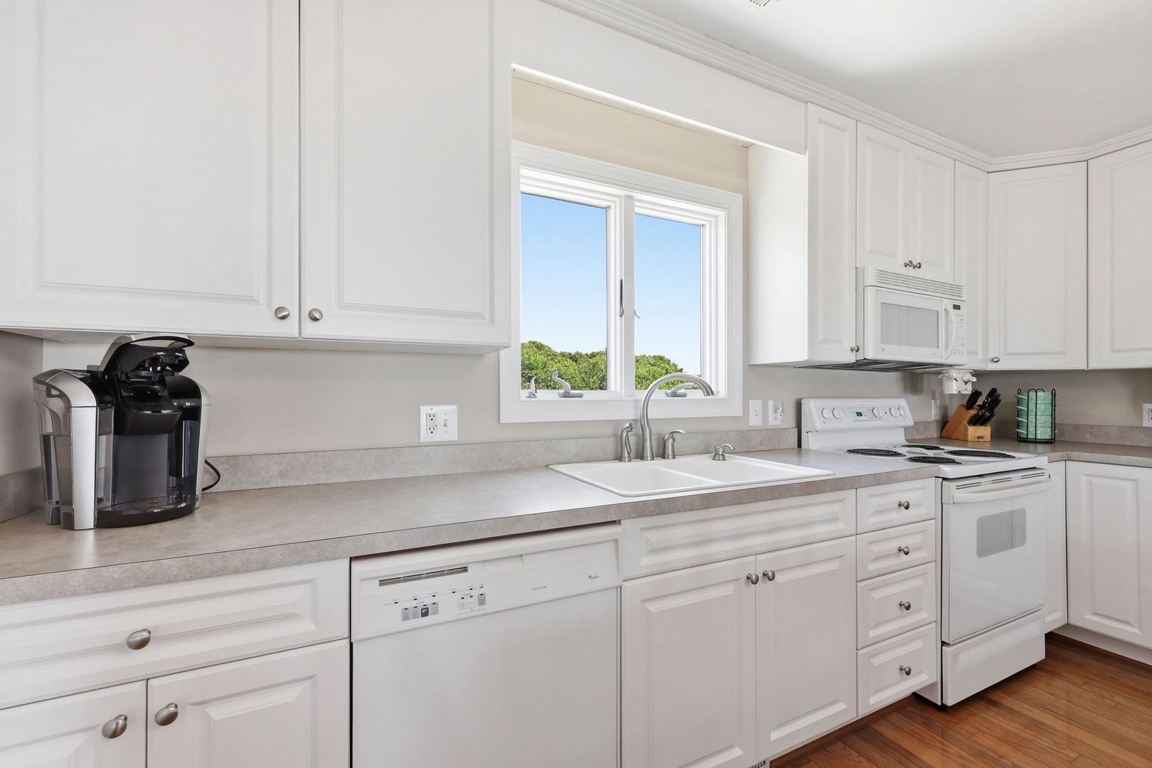 Bright, all-white kitchen with modern appliances, ample counter space, and natural light. Equipped with a coffee maker and everything you need for easy meal prep during your stay.