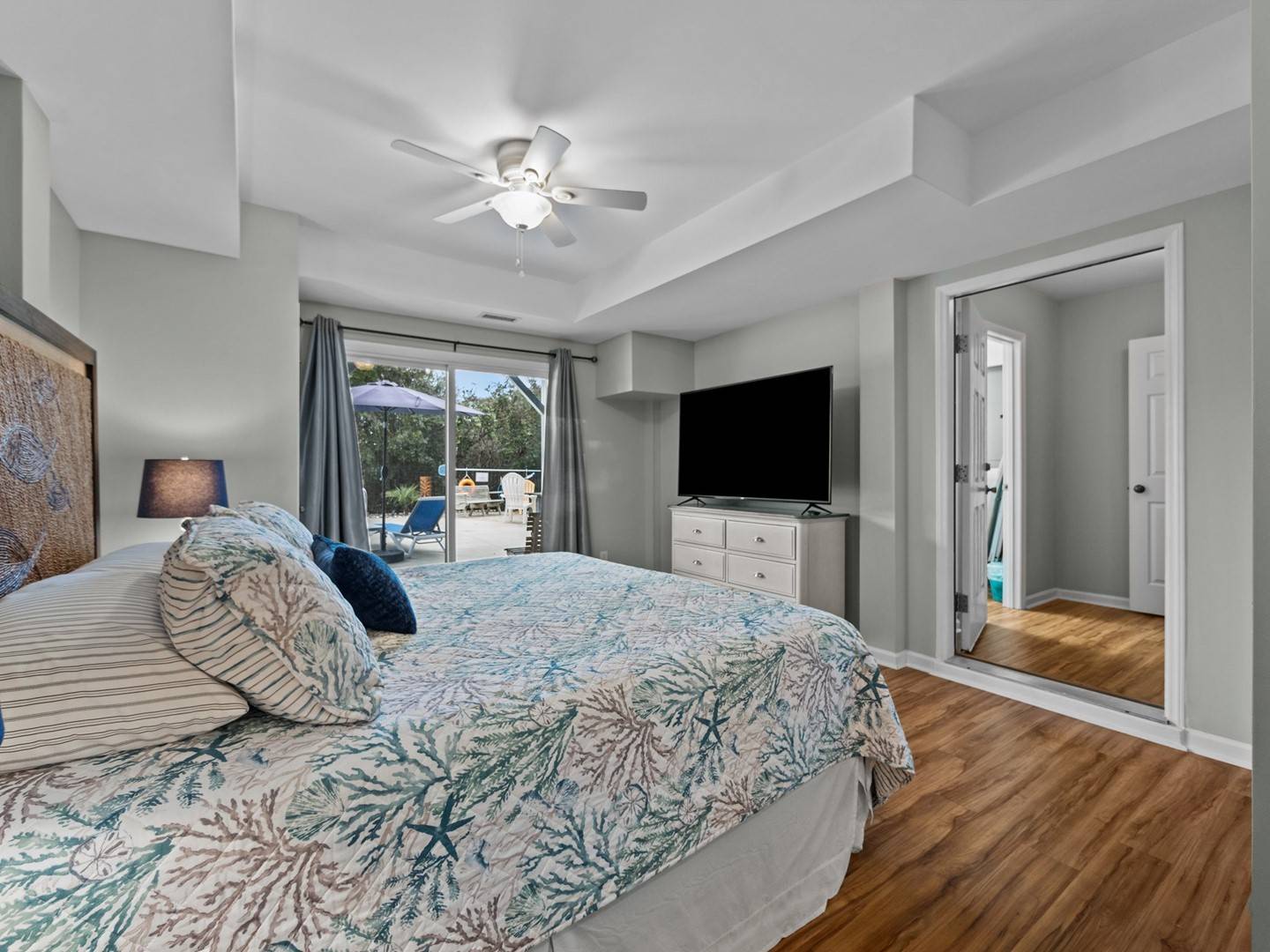 Your peaceful master bedroom features coastal-themed bedding and private patio access for morning coffee in the sunshine.