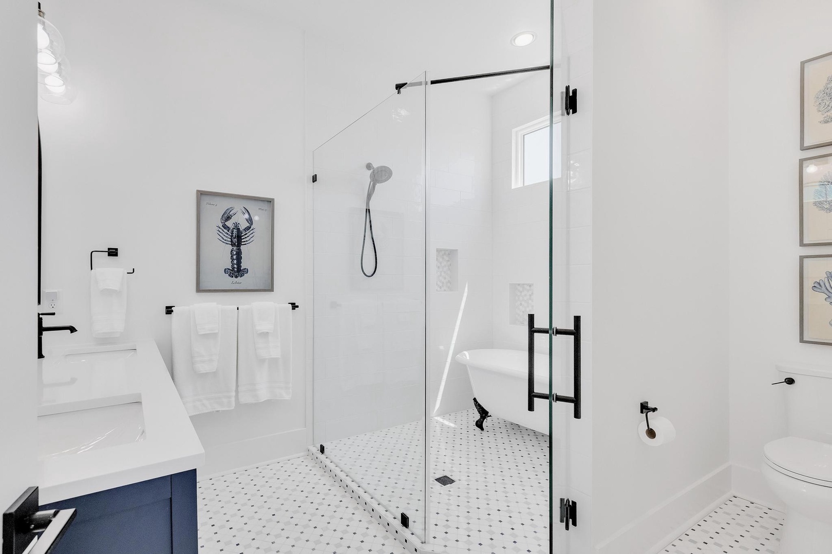Step into a bright, modern bathroom with a spacious glass-enclosed shower, sleek black fixtures, and coastal artwork adding character to your clean, comfortable retreat.