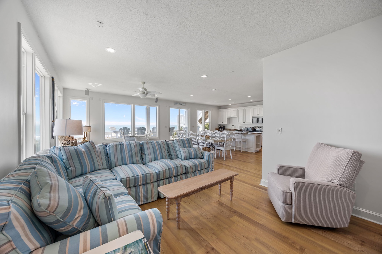 Relax in your bright, airy living space with coastal-striped seating and panoramic windows that fill the room with natural light and ocean views.