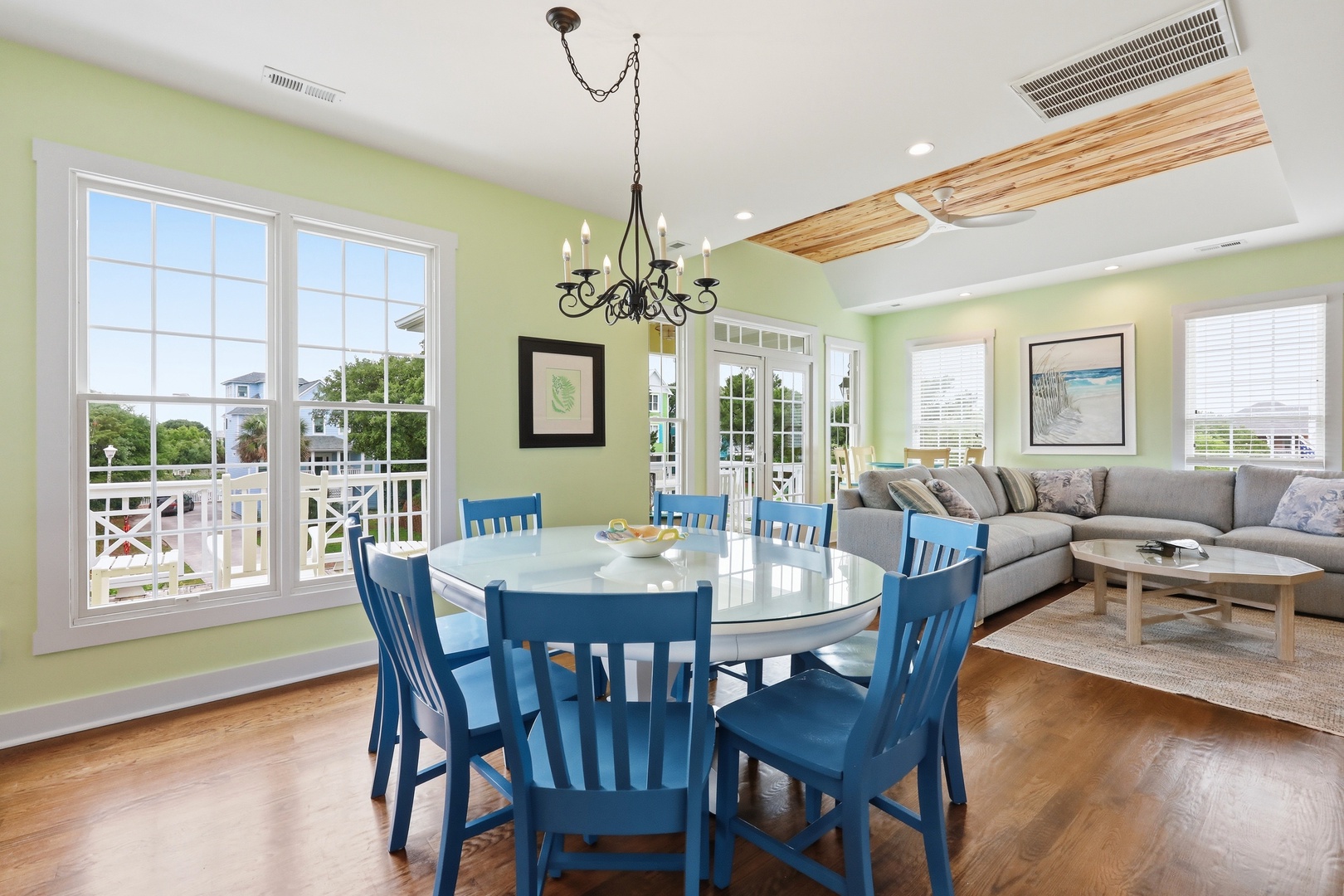 Gather around this bright dining space where coastal charm meets comfort. Soft green walls and ocean-inspired décor invite you to share meals while natural light floods in through large windows overlooking the neighborhood.