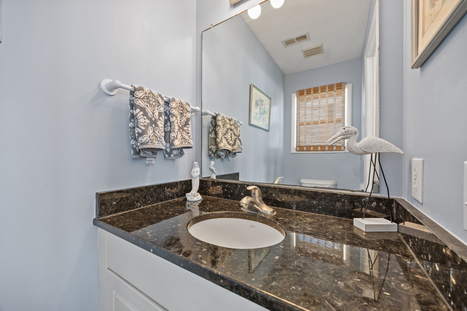 You'll feel refreshed in this elegant bathroom featuring granite countertops, decorative towels, and coastal touches.