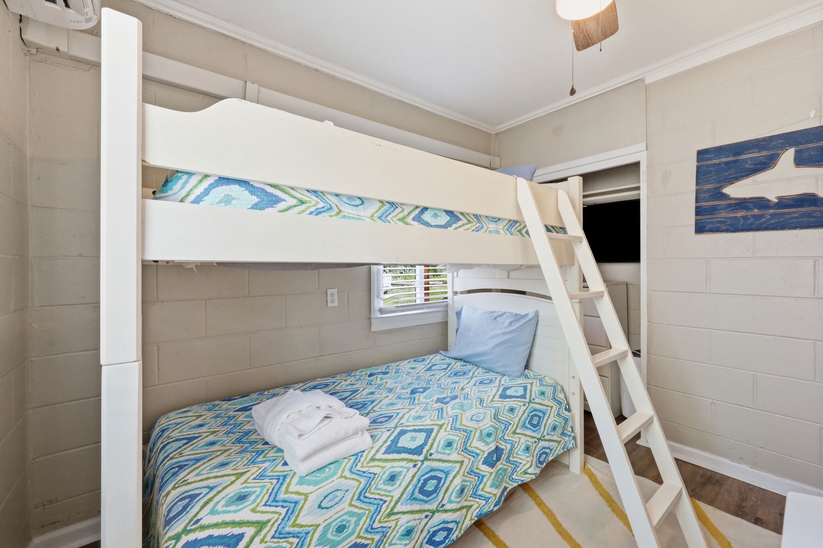 Climb up to your cozy coastal retreat where cheerful blue and green bedding creates a beach-inspired haven for restful nights and lazy mornings.