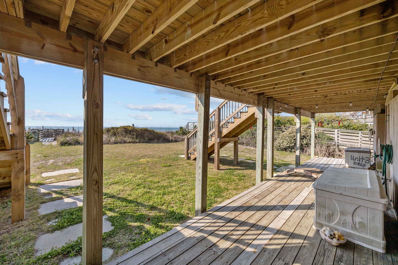 Your covered deck opens to ocean views and beach access, with warm wooden beams creating the perfect coastal retreat.