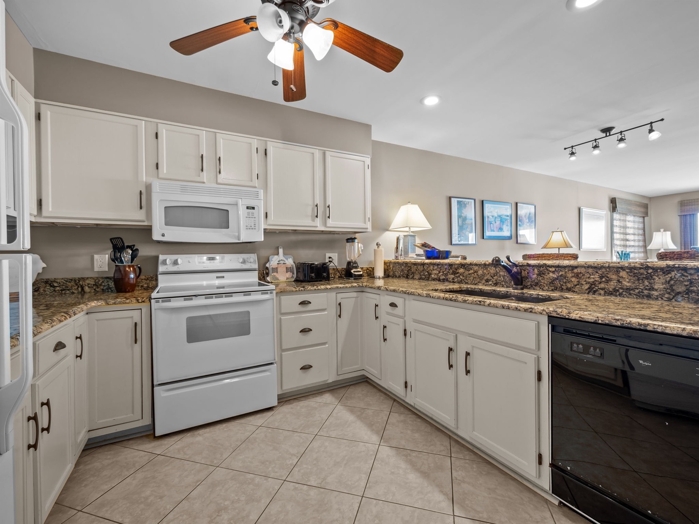 Your fully equipped kitchen features granite countertops, white appliances, and ample cabinet space for preparing memorable vacation meals.