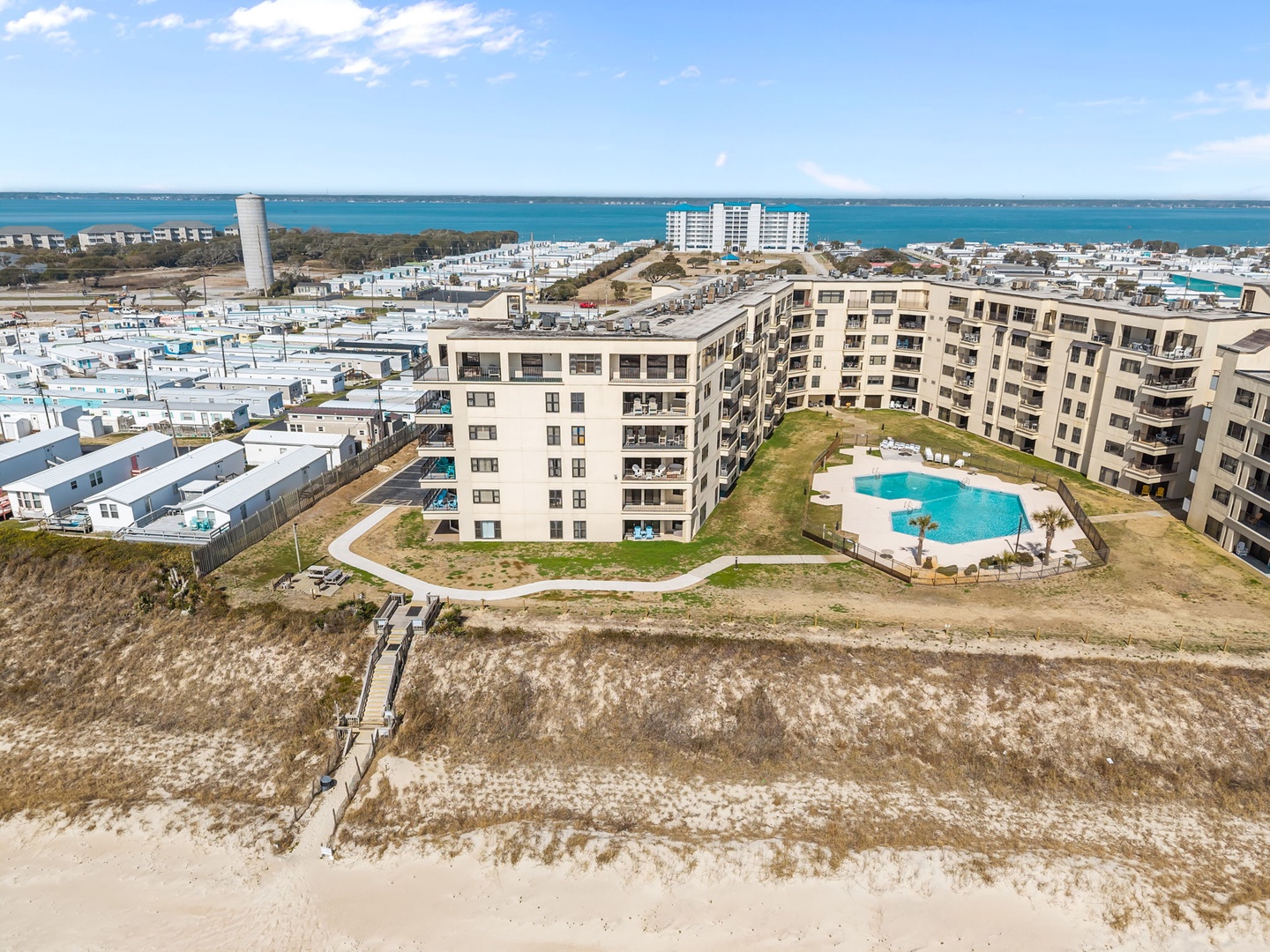 Modern beachfront property complex featuring direct beach access, outdoor pool, and coastal neighborhood setting with ocean views.
