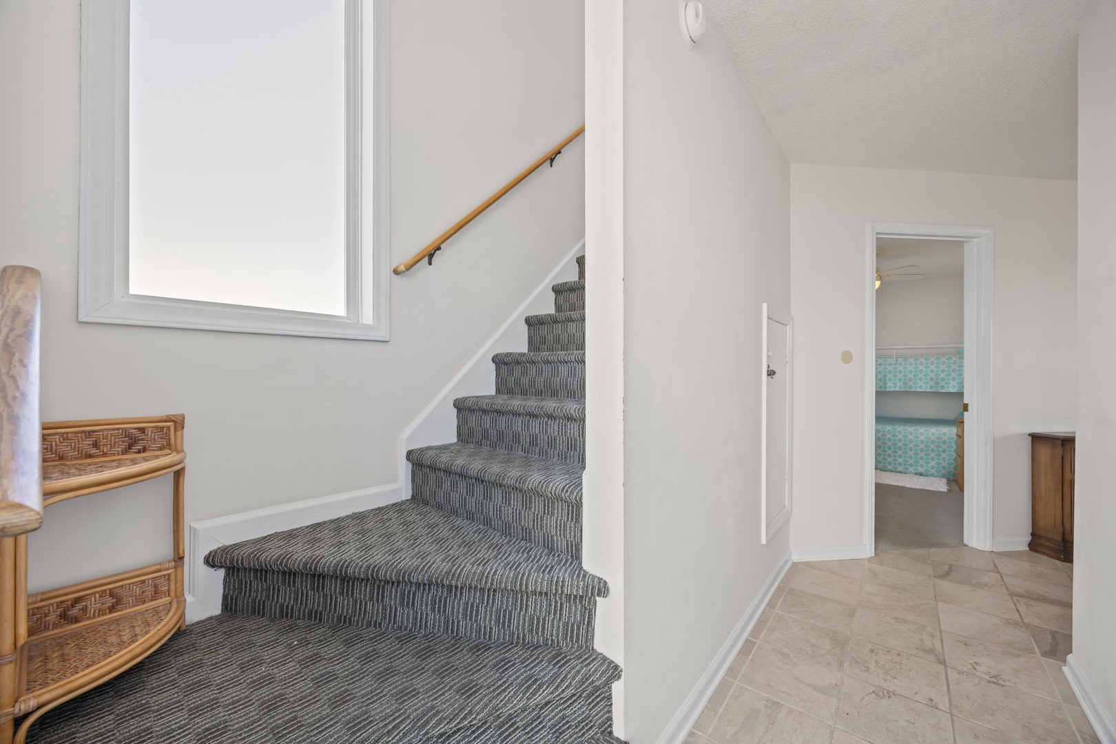 Step into your bright, welcoming entryway where natural light fills the space and carpeted stairs lead to your upstairs retreat.