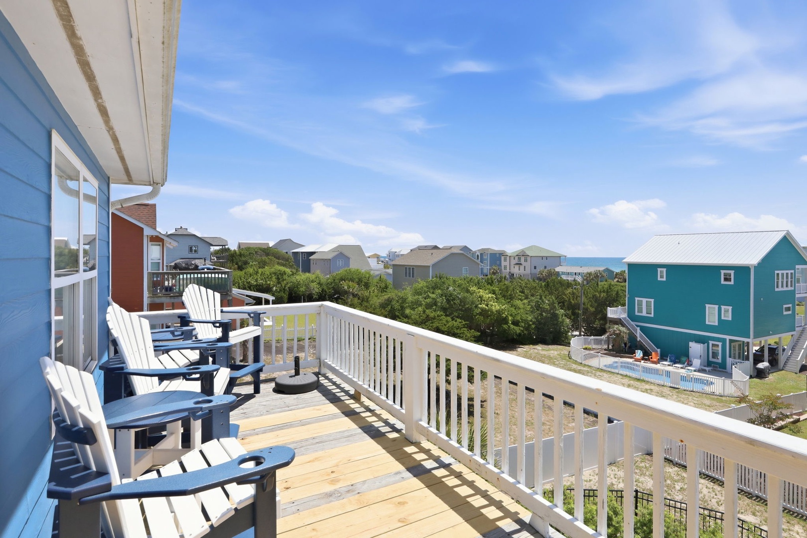 Coastal neighborhood with colorful beach houses, green dunes, and a glimpse of the ocean beyond—a serene setting for your beach getaway.