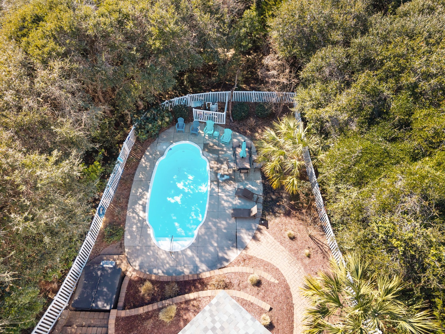 Aerial view of private pool area surrounded by lush vegetation and outdoor seating spaces.
