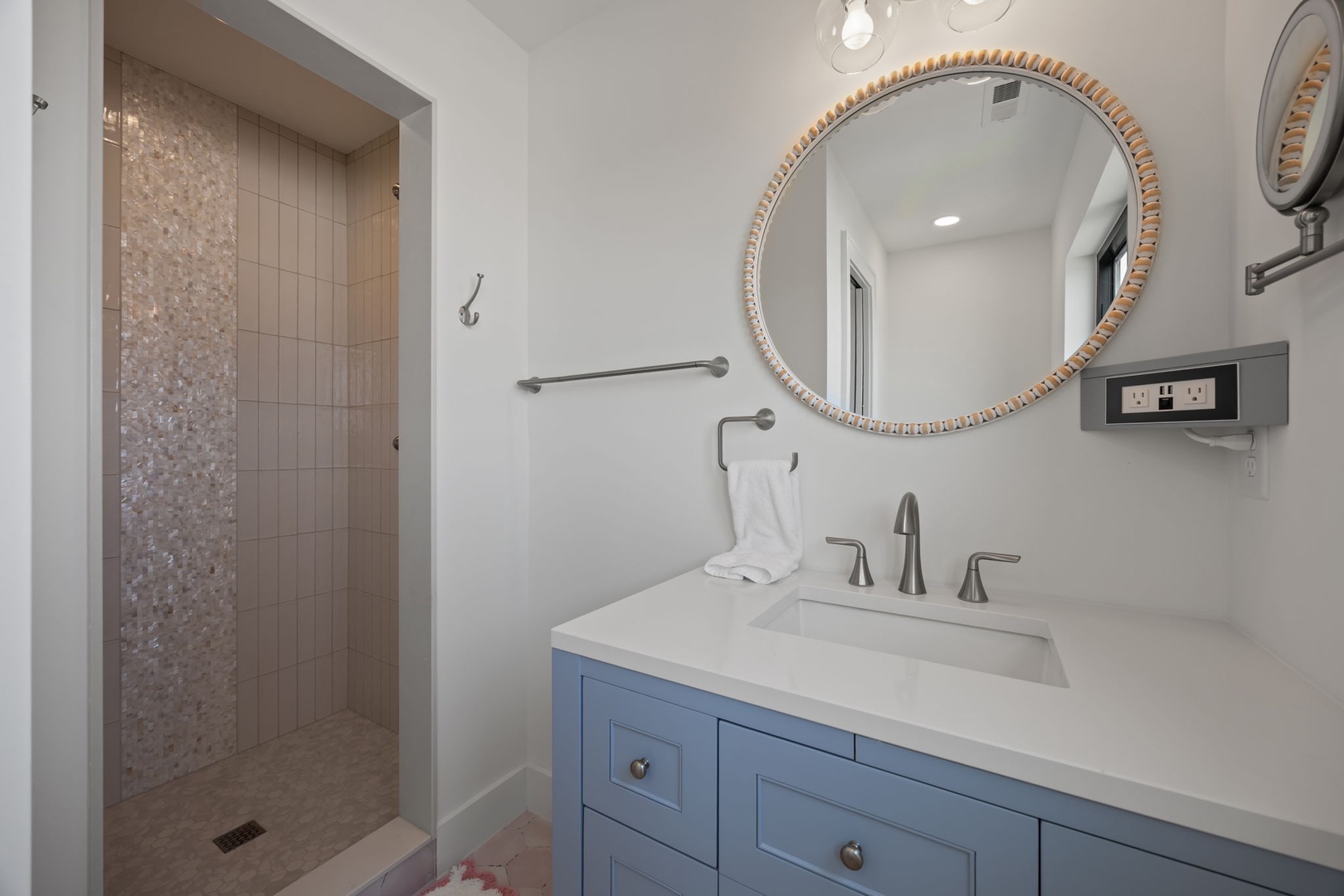 Refresh in your elegant ensuite with marble countertops, stylish blue vanity, and luxurious walk-in shower featuring stunning mosaic details.