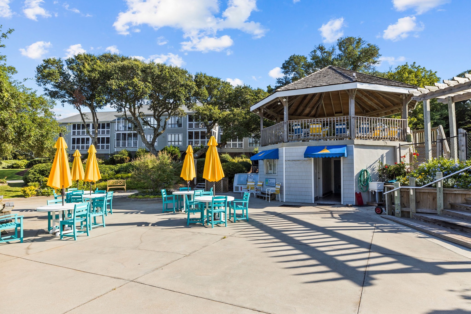 Vibrant poolside dining area with sunny yellow umbrellas and turquoise tables creates the perfect spot for your morning coffee or afternoon refreshments.