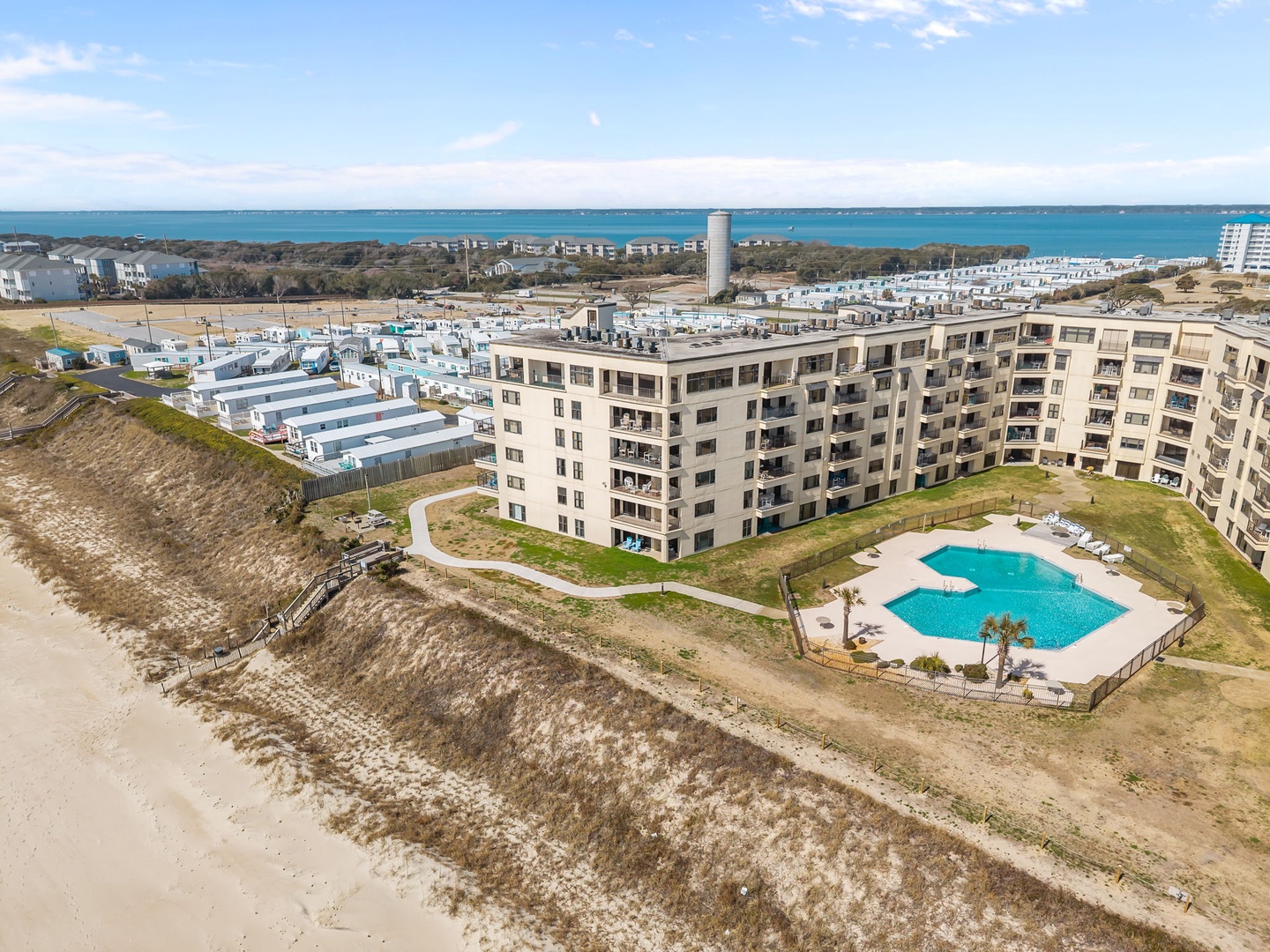 Beachfront resort property with ocean access and a sparkling pool, set along the coast with views of the bay and surrounding area.