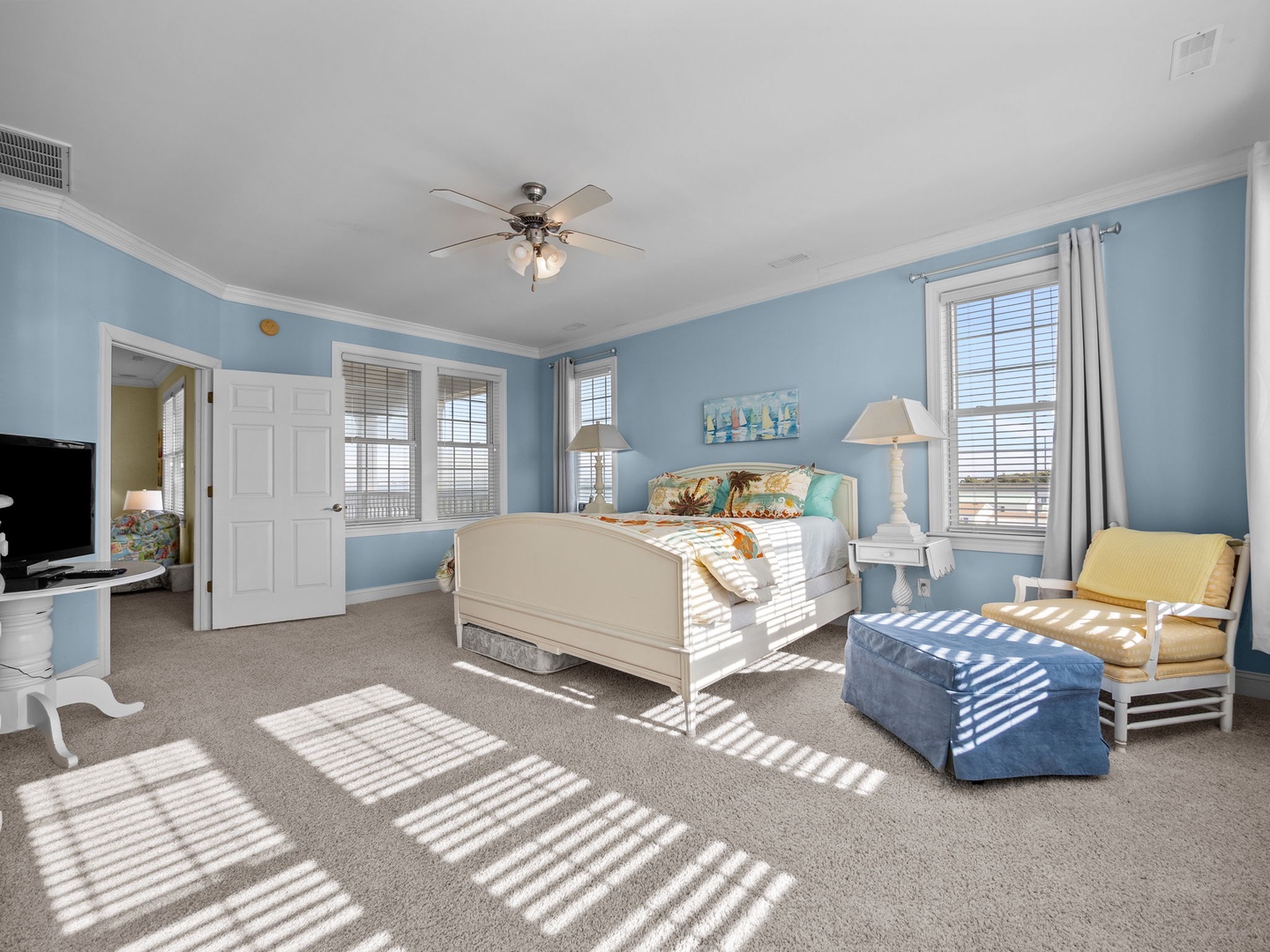 Sink into your coastal-themed bedroom where ocean-blue walls and sunlight streaming through windows create a tranquil retreat for restful nights.