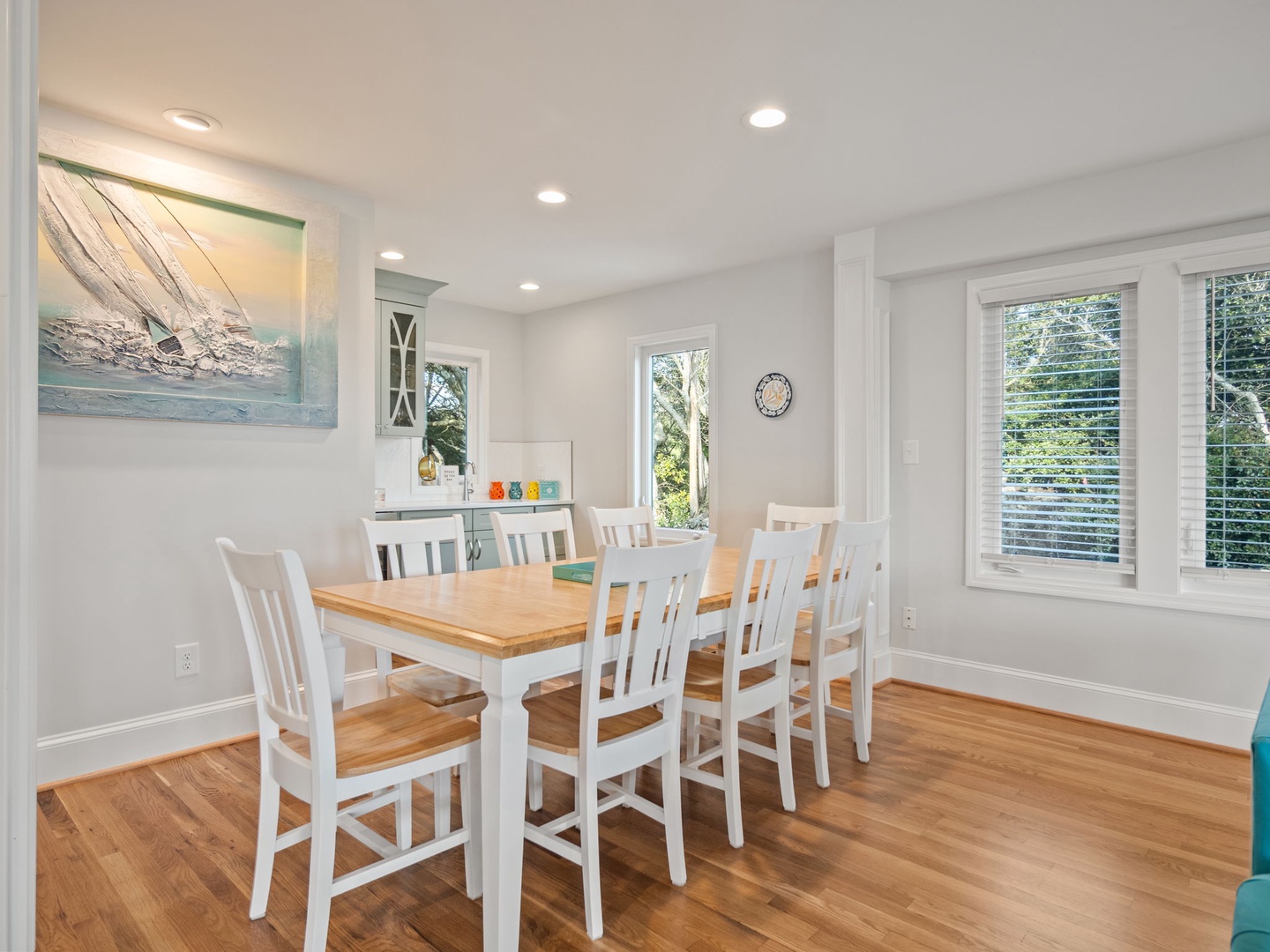 Gather your group around this bright dining table where natural light streams through generous windows, creating the perfect space for memorable meals together.