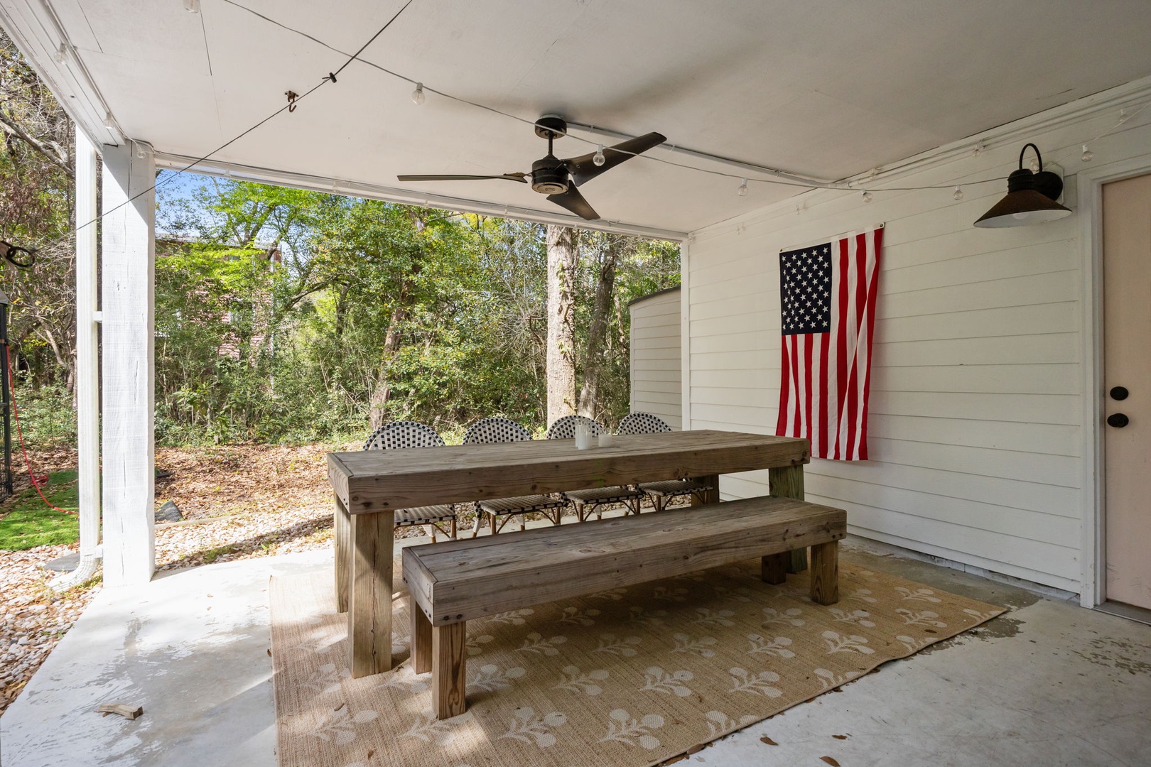 Gather around your private covered patio with rustic dining table and benches, perfect for morning coffee or evening meals under twinkling lights.