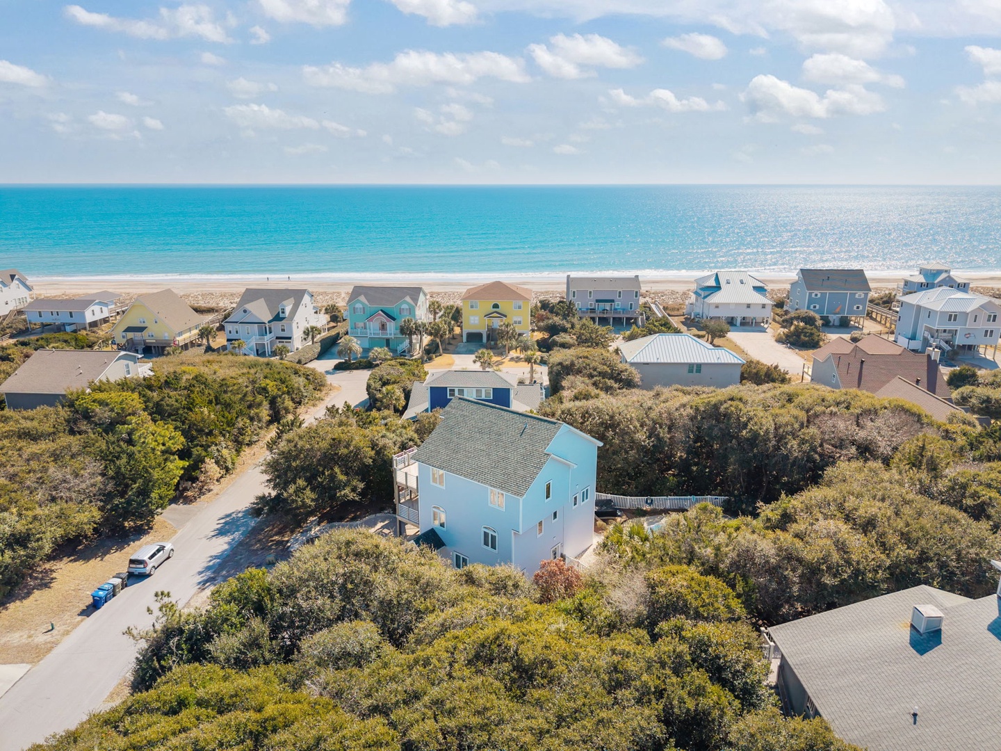 Charming coastal community with colorful beachfront homes nestled among native vegetation, just steps from pristine sandy shores.