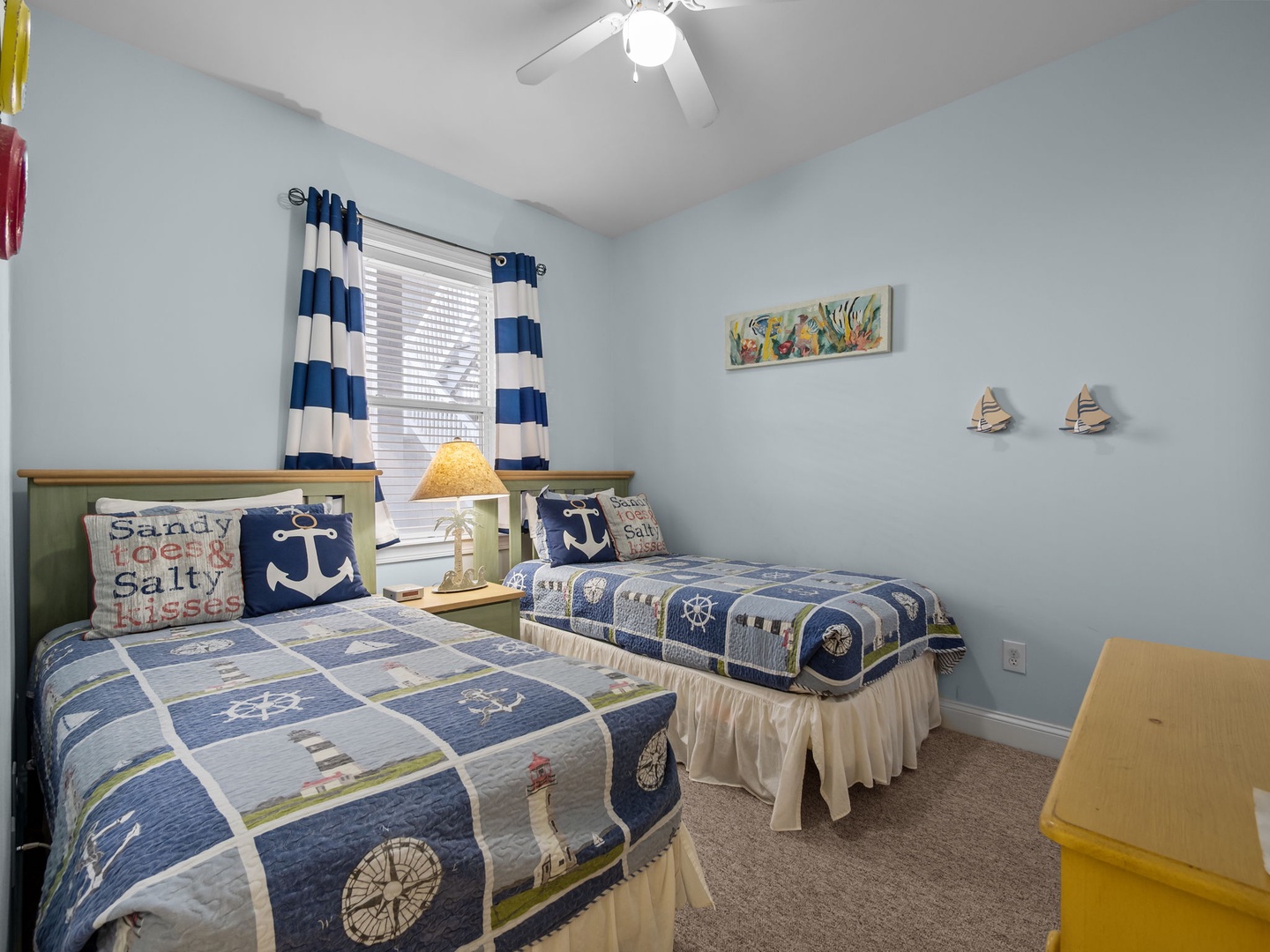 Your cozy nautical-themed bedroom features twin beds with charming ocean decor, perfect for kids or friends sharing seaside dreams.