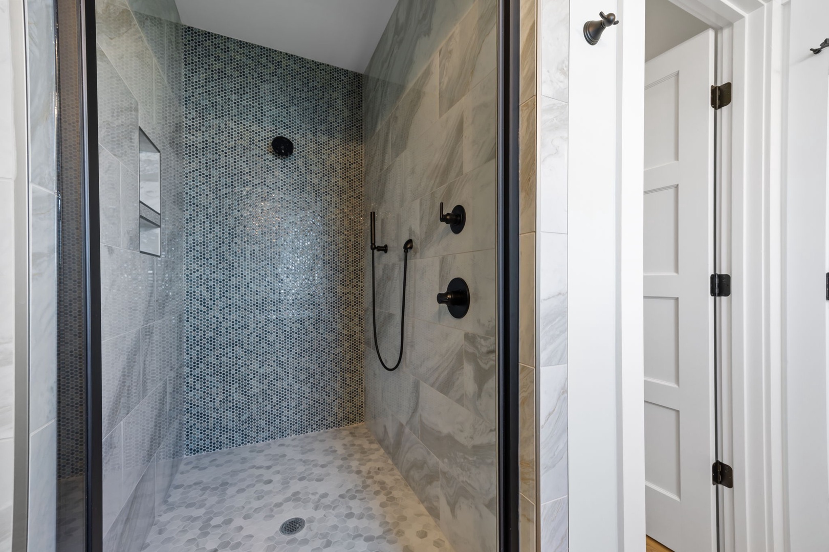 Step into your luxurious walk-in shower with stunning mosaic tile accent wall and rainfall showerhead for a spa-like experience.