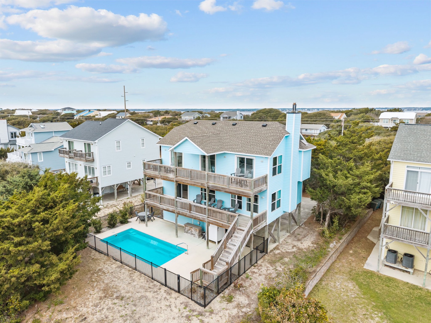 Aerial view of beachfront vacation homes nestled among coastal vegetation, with swimming pools and easy beach access in this scenic waterfront community.